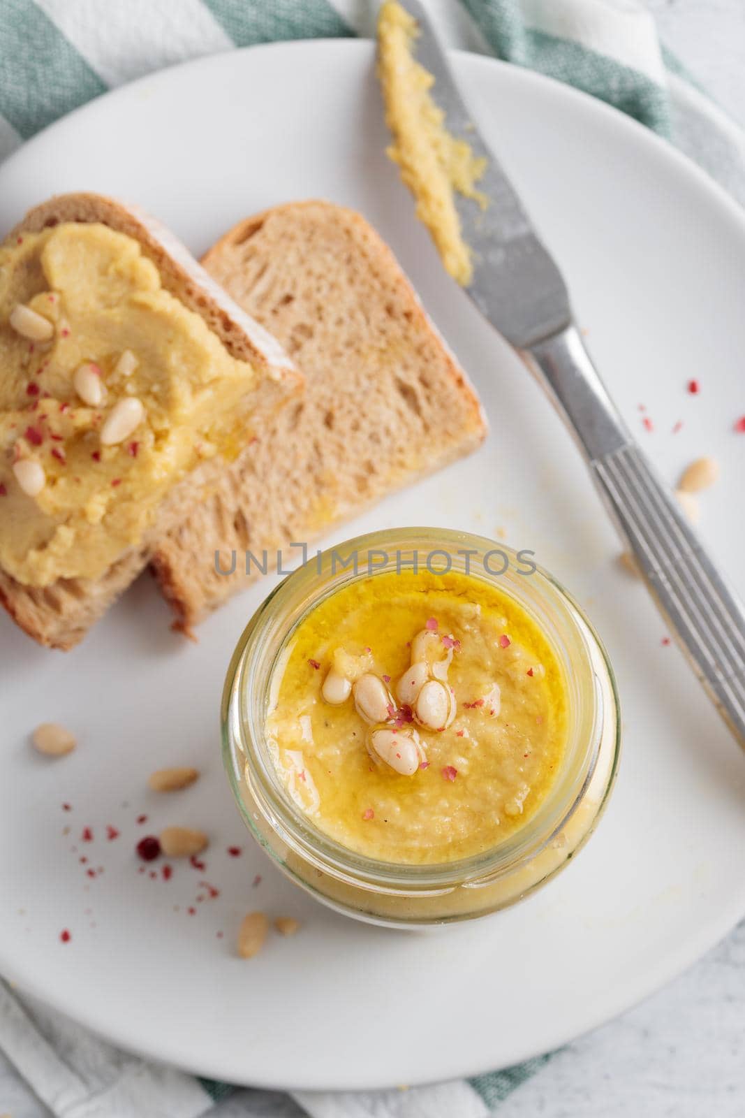 Homemade hummus with pine nuts and bread on a plate
