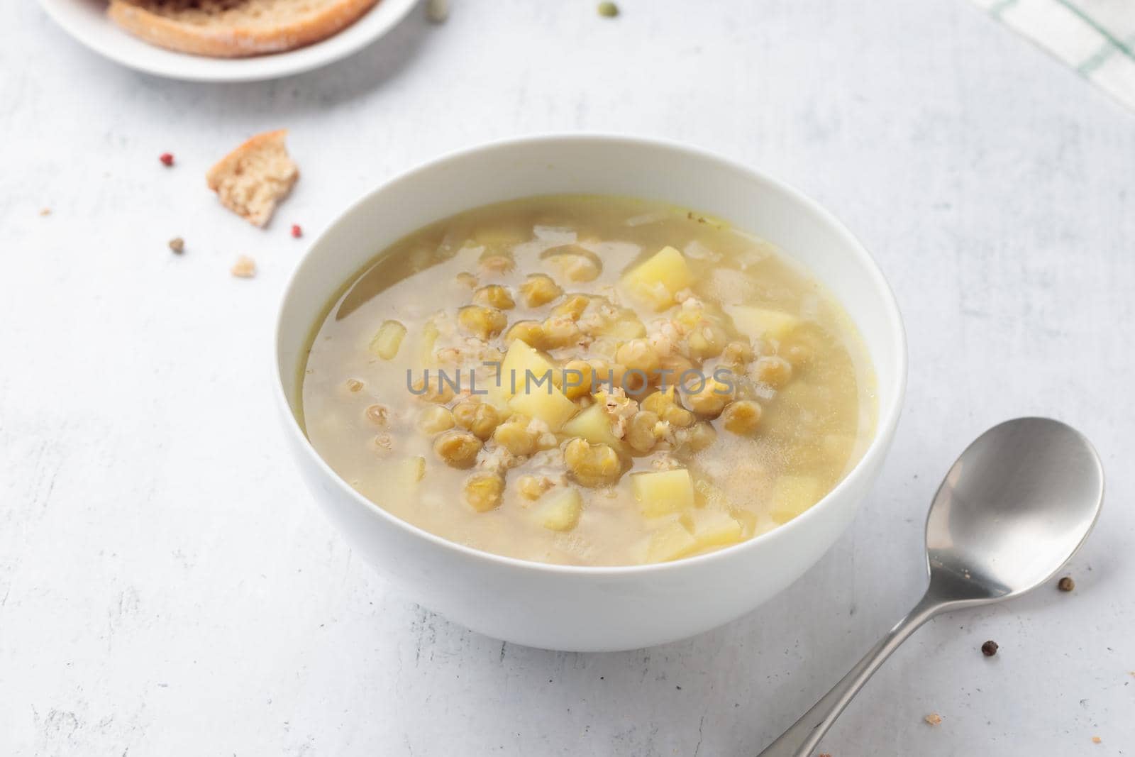 Green pea soup in a large white bowl on a table