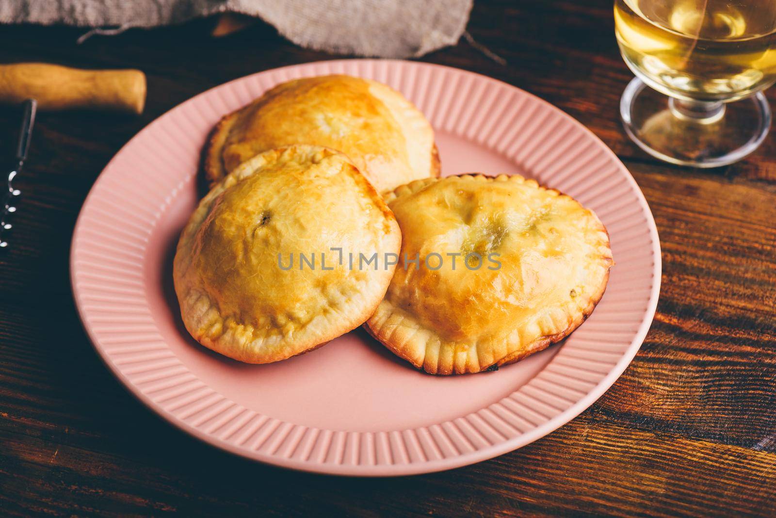 Three Oven Baked Hand Pies Filled with Blue Chives and Mushrooms on Plate with Glass of Wine