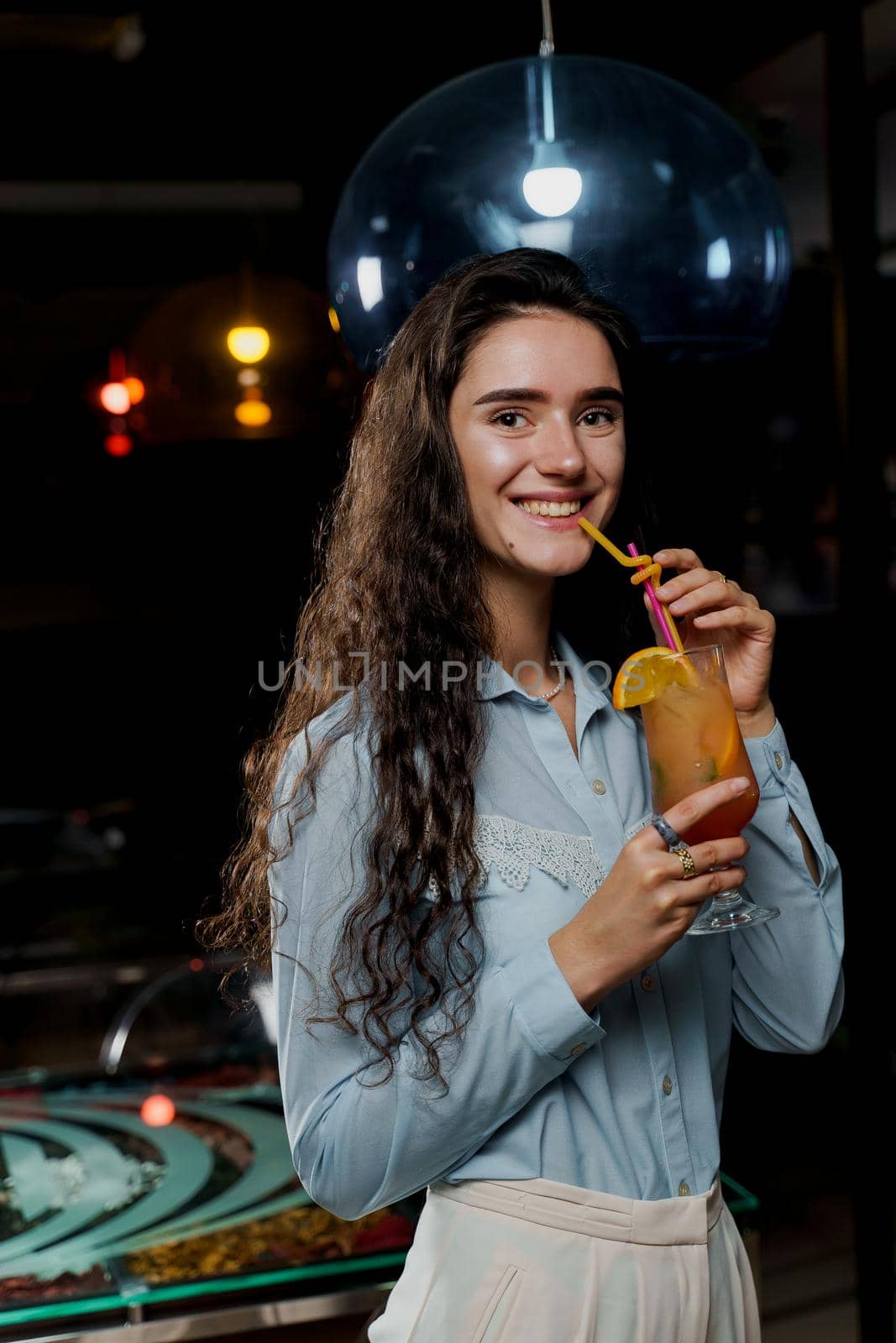 Girl with cocktail is drinking in night club before party. Advert for bar and night clubs. Citrus alcohol drink with orange juice