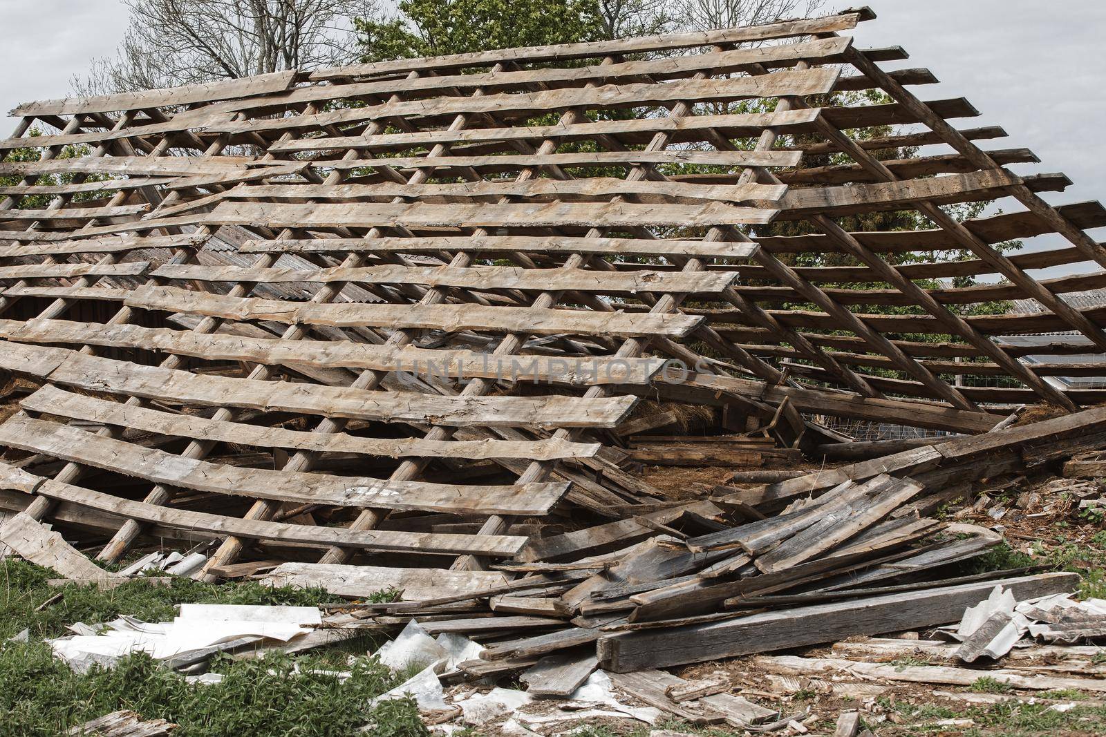 Old ruined house with a holey roof. Removed slate roof tiles on a pitched roof on a derelict house