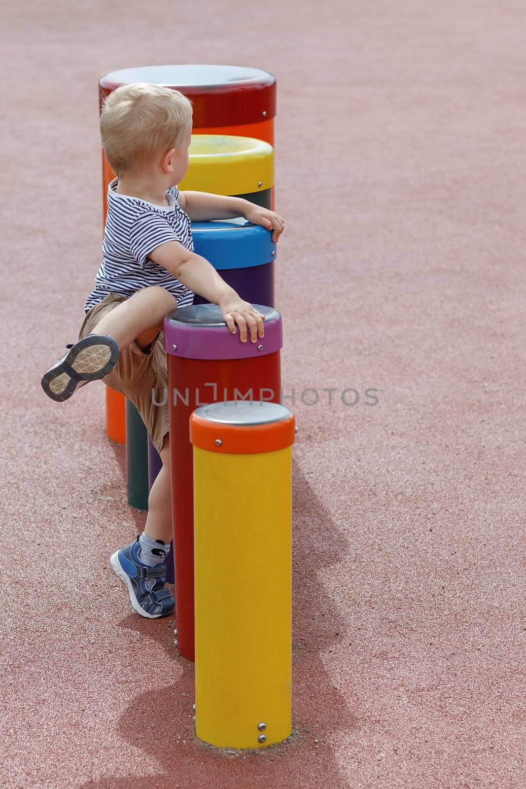 Colorful drums line and unstoppable child in a playground by Lincikas