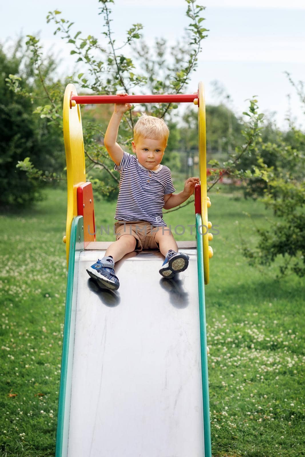 Childhood joys on a slide in summer time by Lincikas