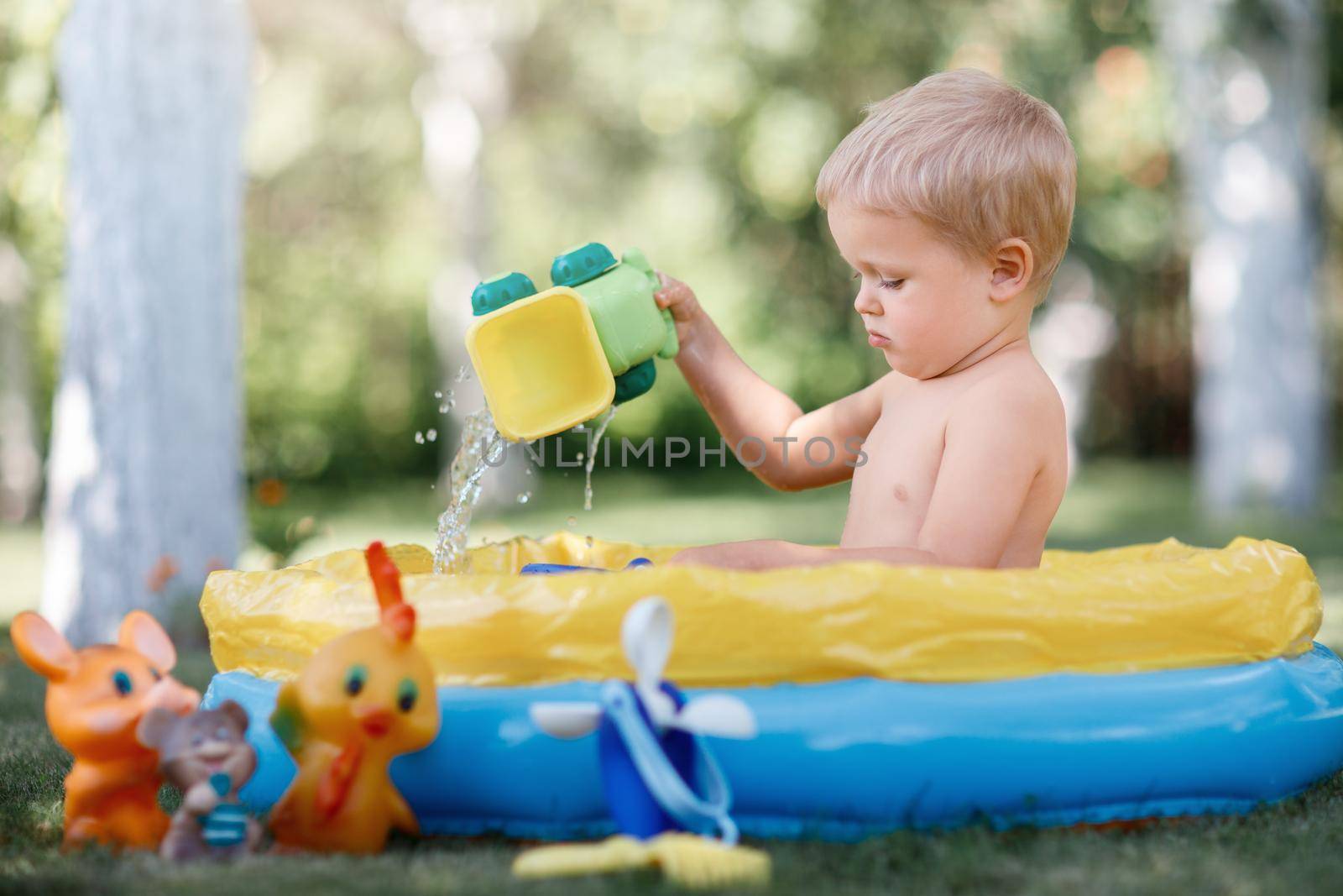 Child plays with water toys in a pool by Lincikas