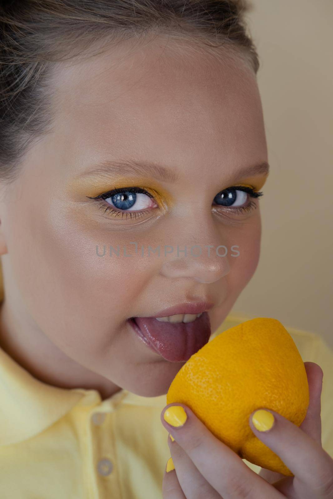 charming tween girl with slices of ripe lemon on yellow background. juicy fruit concept. summer.