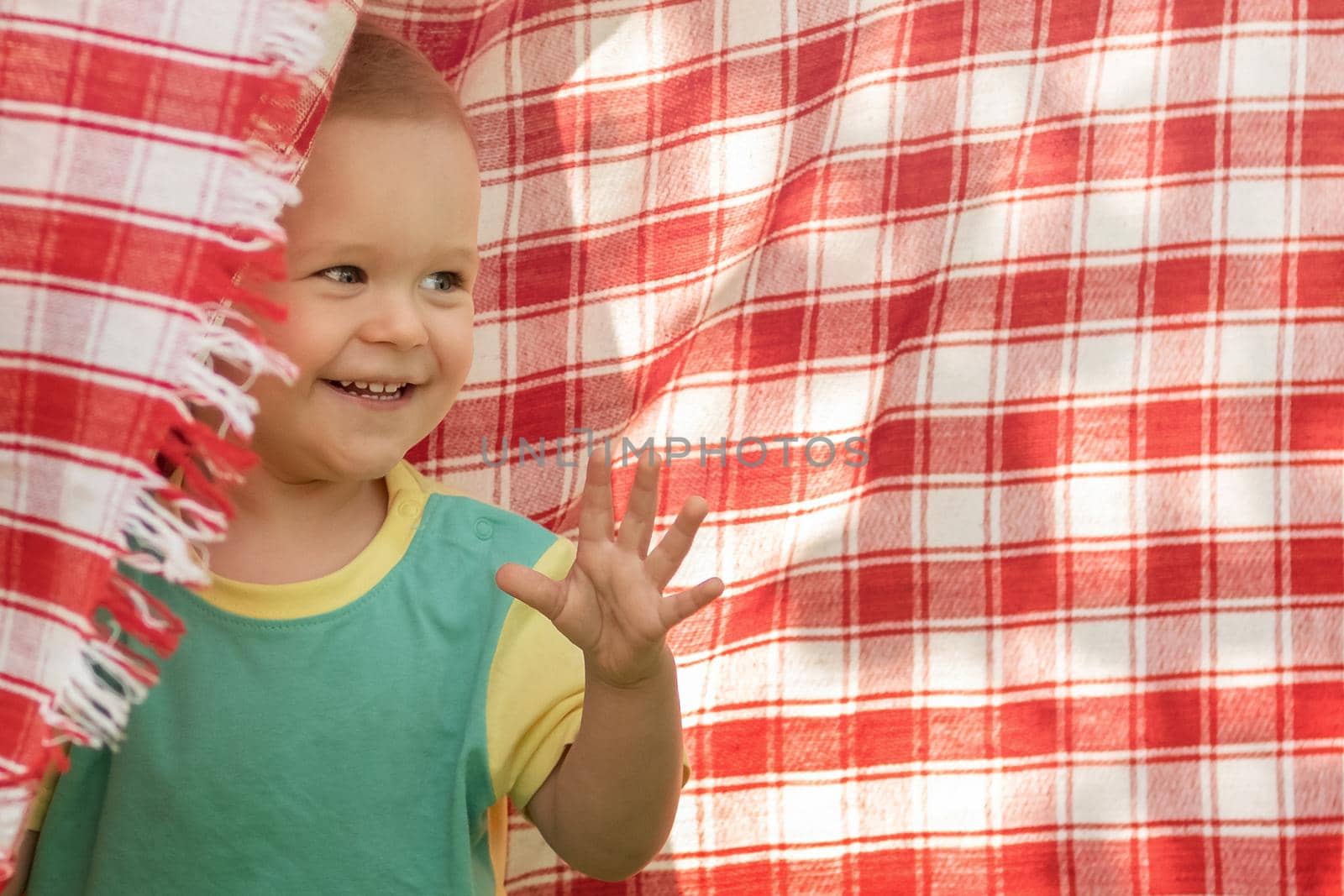 Happy little boy playing in the red checkered  shawl background