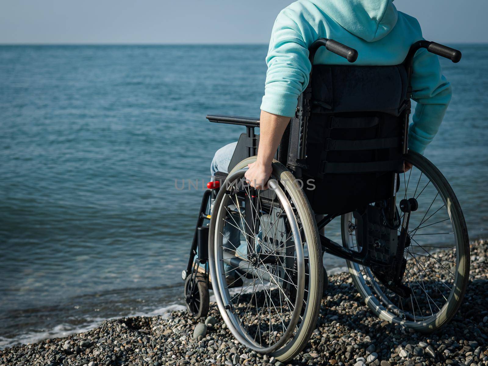 Caucasian woman in a wheelchair on the seashore. Close-up of female hands. by mrwed54