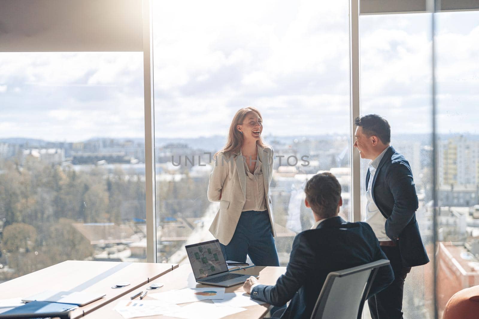 Team of young businessmen communicating together in modern office with panoramic windows by Yaroslav_astakhov