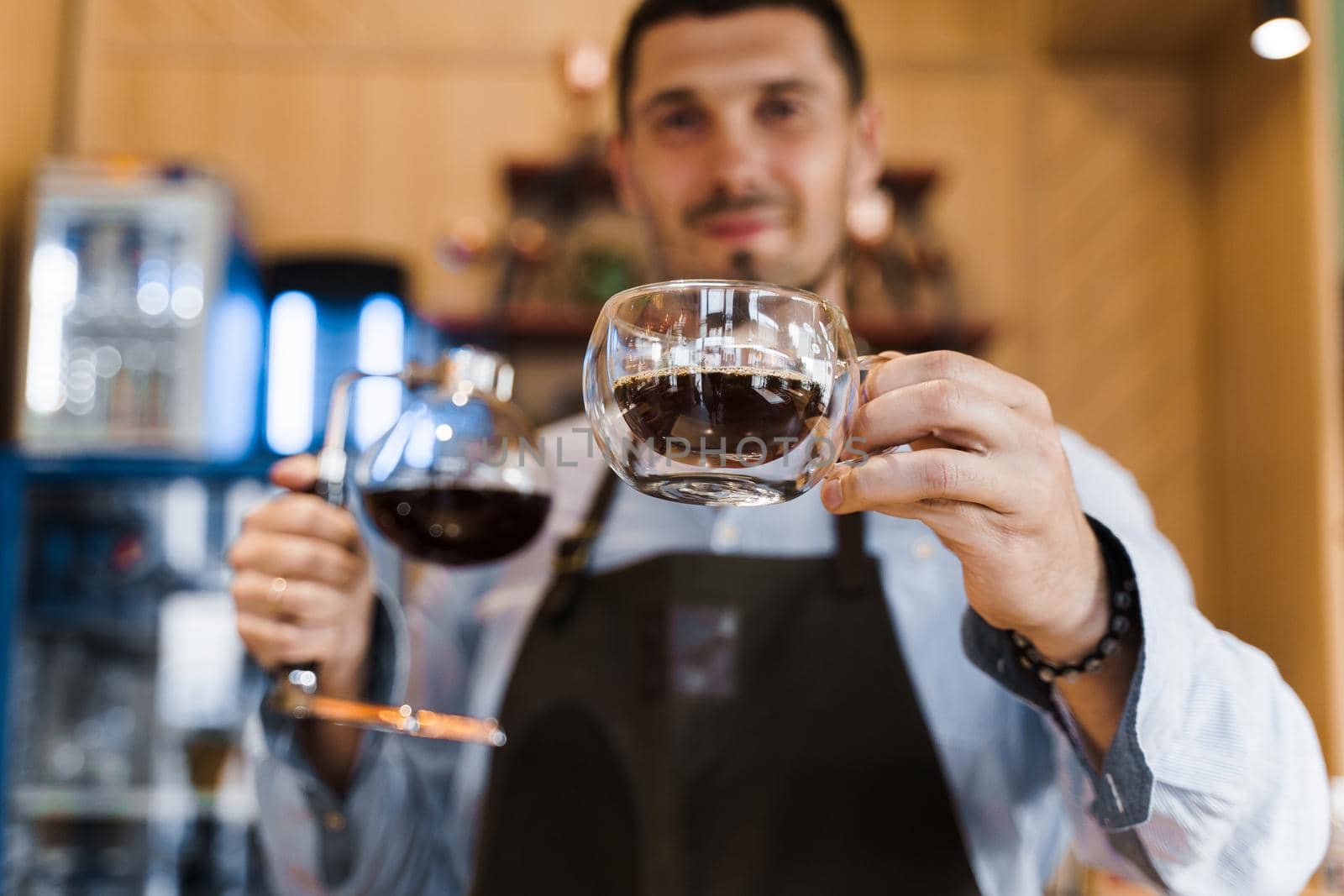 Syphon alternative method of making coffee. Barista gives hot coffee in double glass cup to customers. Coffee brewing in cafe