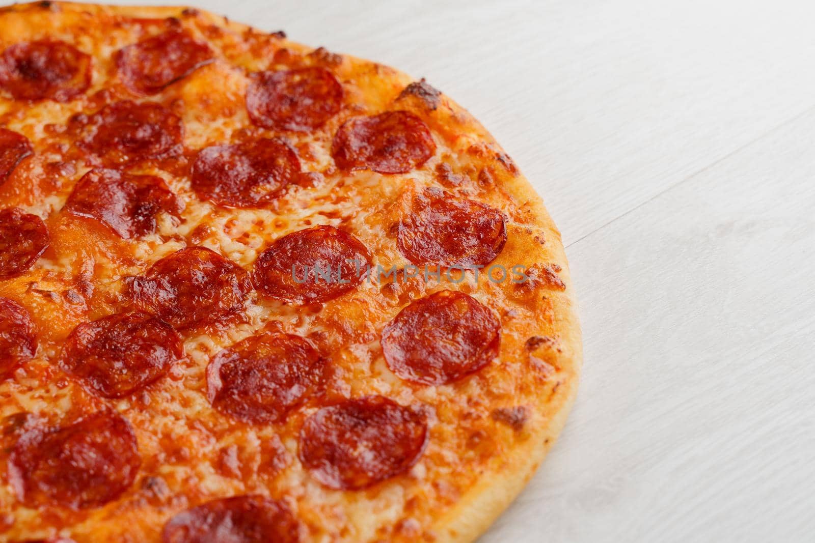 Peperoni pizza with salami, cheese and sauce isolated on white wooden background. Advert for social network of restaurants, caffee. Promotion for pizzeria