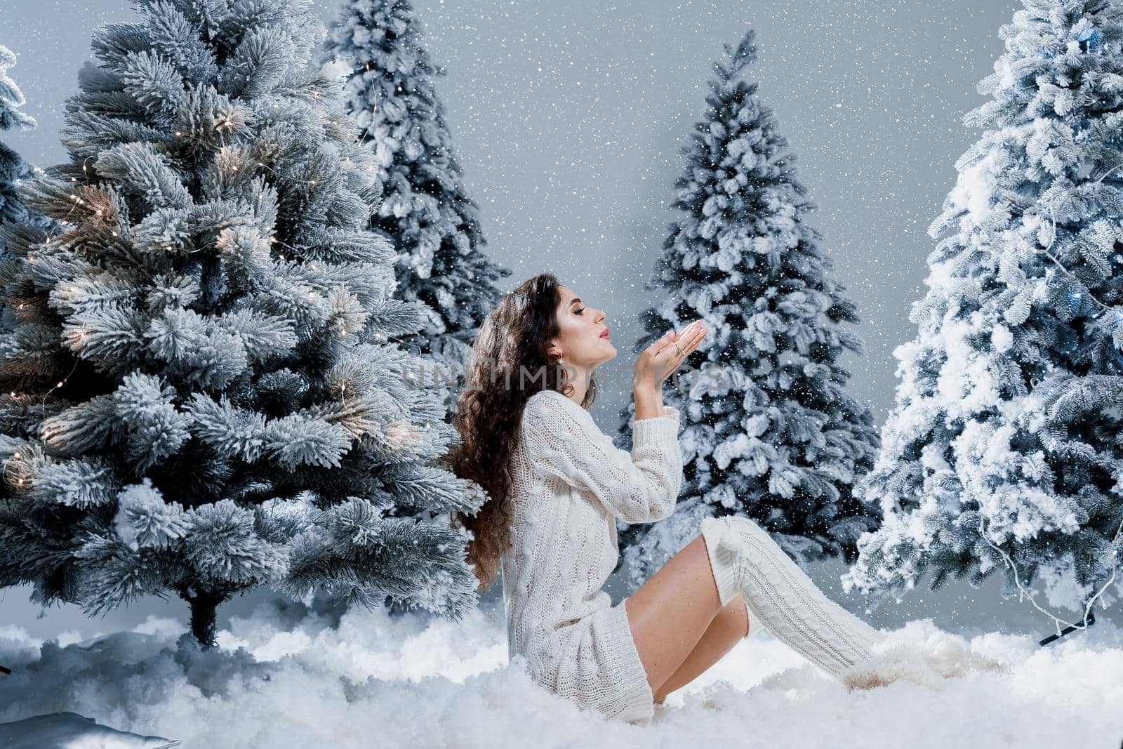 New year celebration. Attractive girl close-up with falling snow . Young woman weared in a warm white pullover and white socks