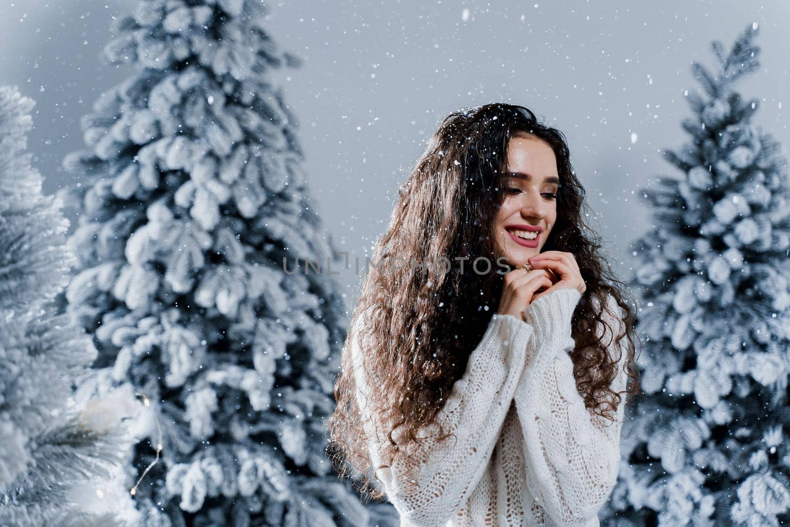 New year celebration.Happy girl with falling snow. Young woman weared in a warm white pullover and white socks. Winter holidays in snowy day