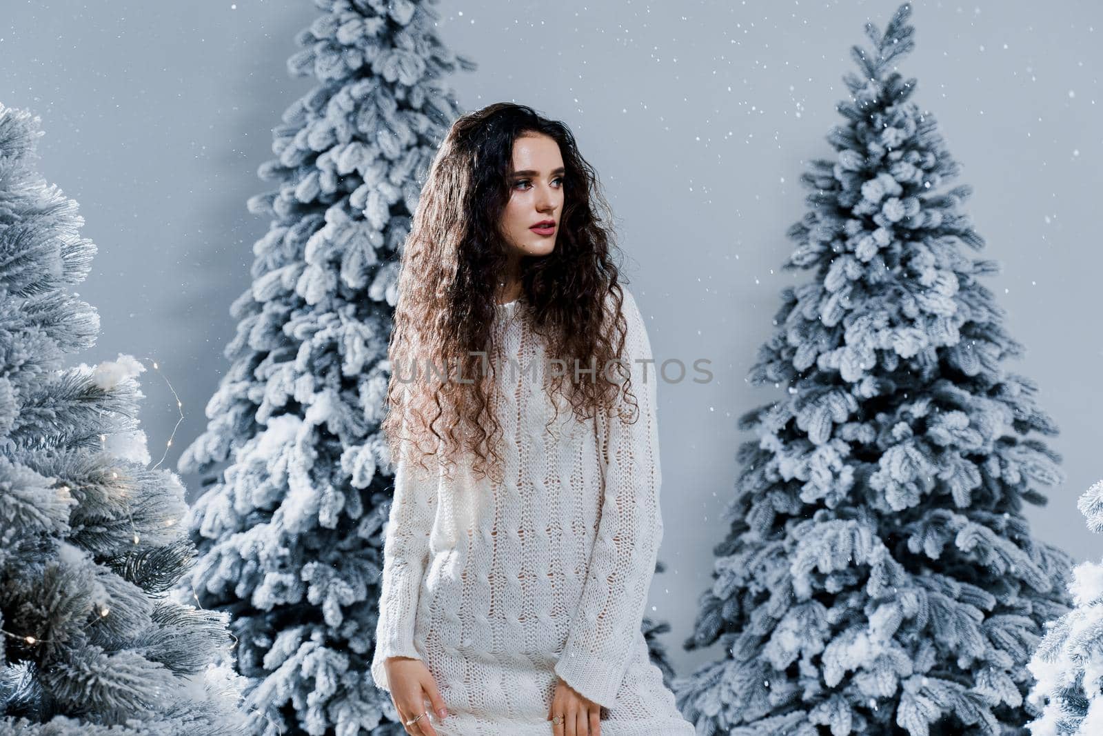 New year celebration.Happy girl with falling snow. Young woman weared in a warm white pullover and white socks. Winter holidays in snowy day