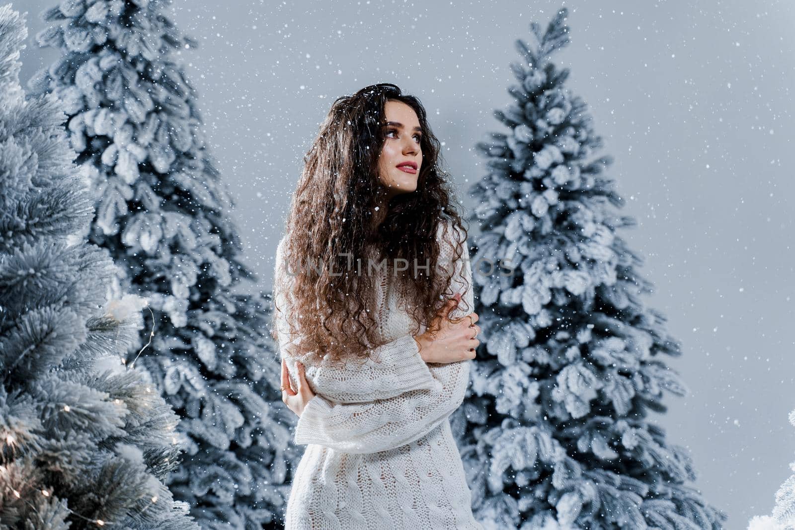 New year celebration.Happy girl with falling snow. Young woman weared in a warm white pullover and white socks. Winter holidays in snowy day