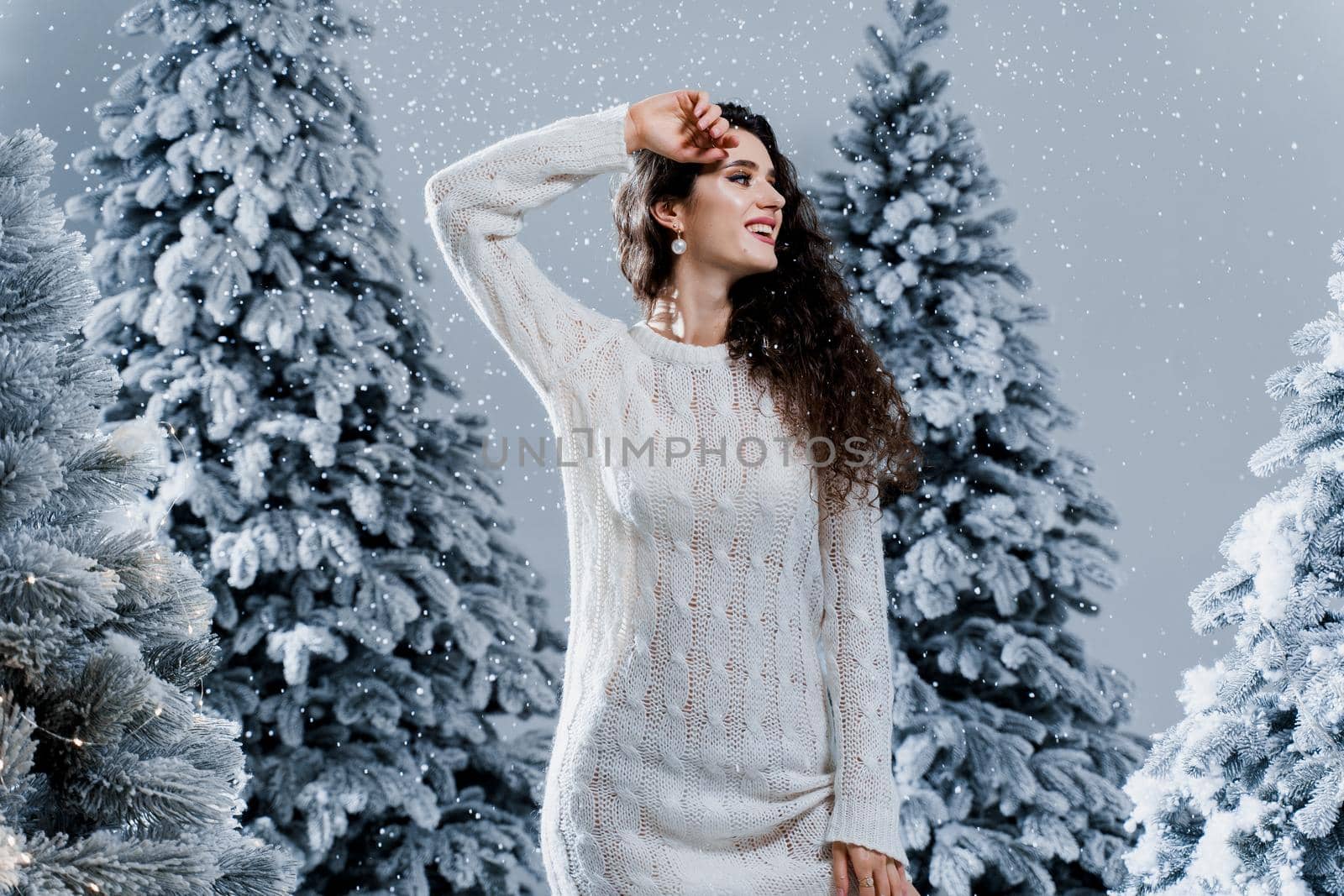 New year celebration.Happy girl with falling snow. Young woman weared in a warm white pullover and white socks. Winter holidays in snowy day