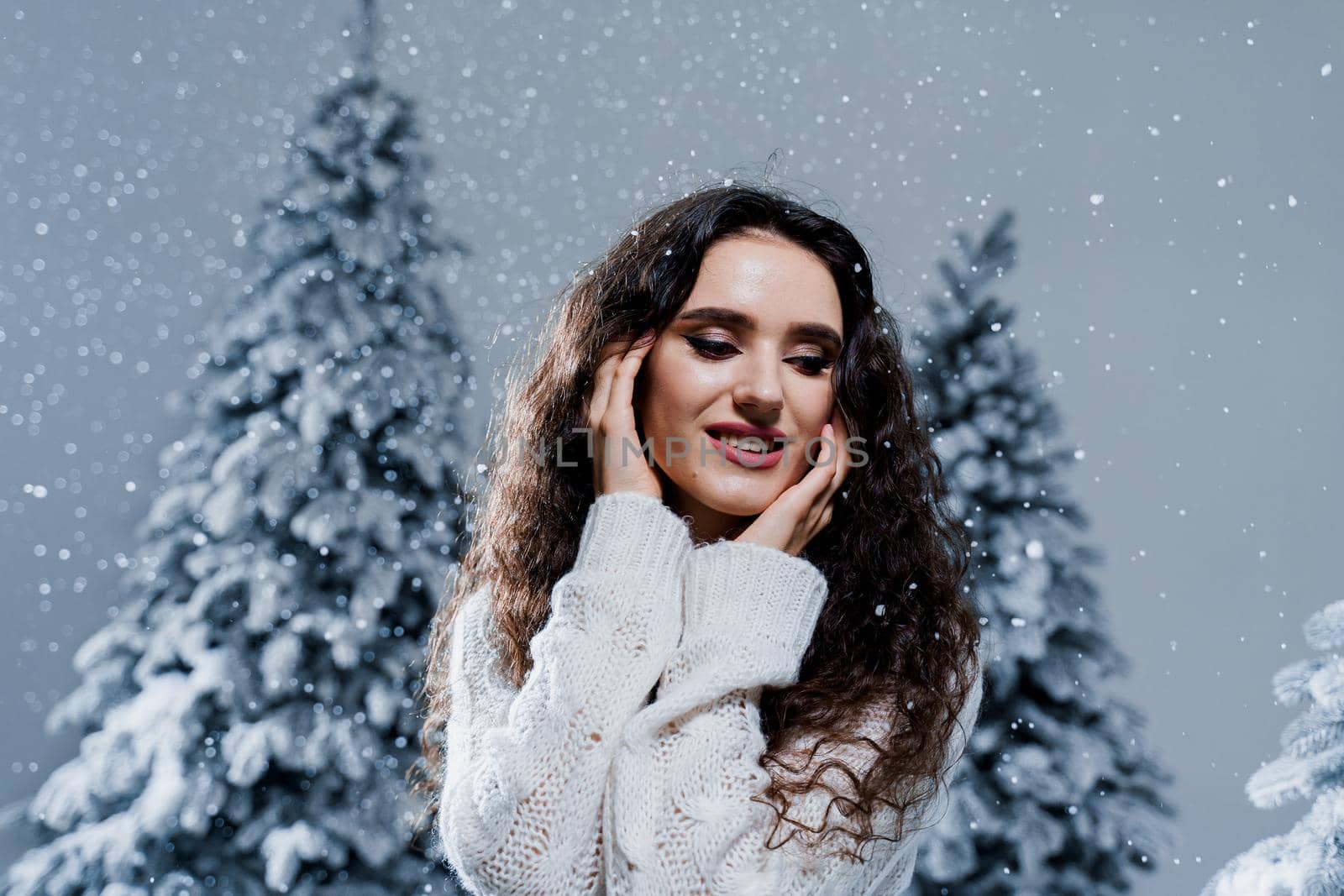 New year celebration.Happy girl with falling snow. Young woman weared in a warm white pullover and white socks. Winter holidays in snowy day