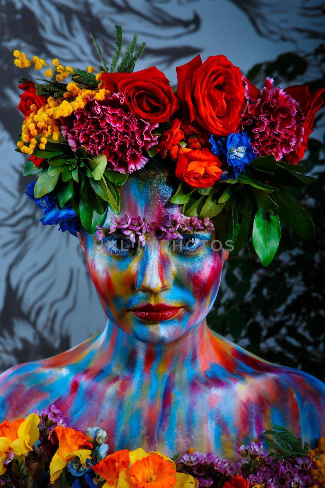 Portrait of a girl whose face is painted with colored paints in a wreath of flowers. In Frida Kahlo's footsteps.