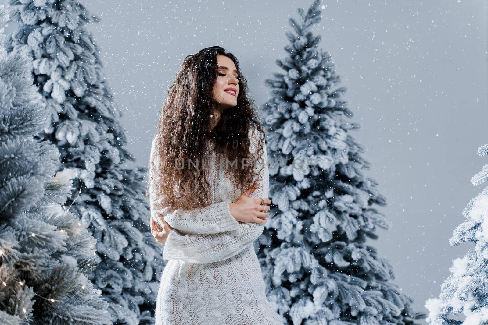 New year celebration.Happy girl with falling snow. Young woman weared in a warm white pullover and white socks. Winter holidays in snowy day