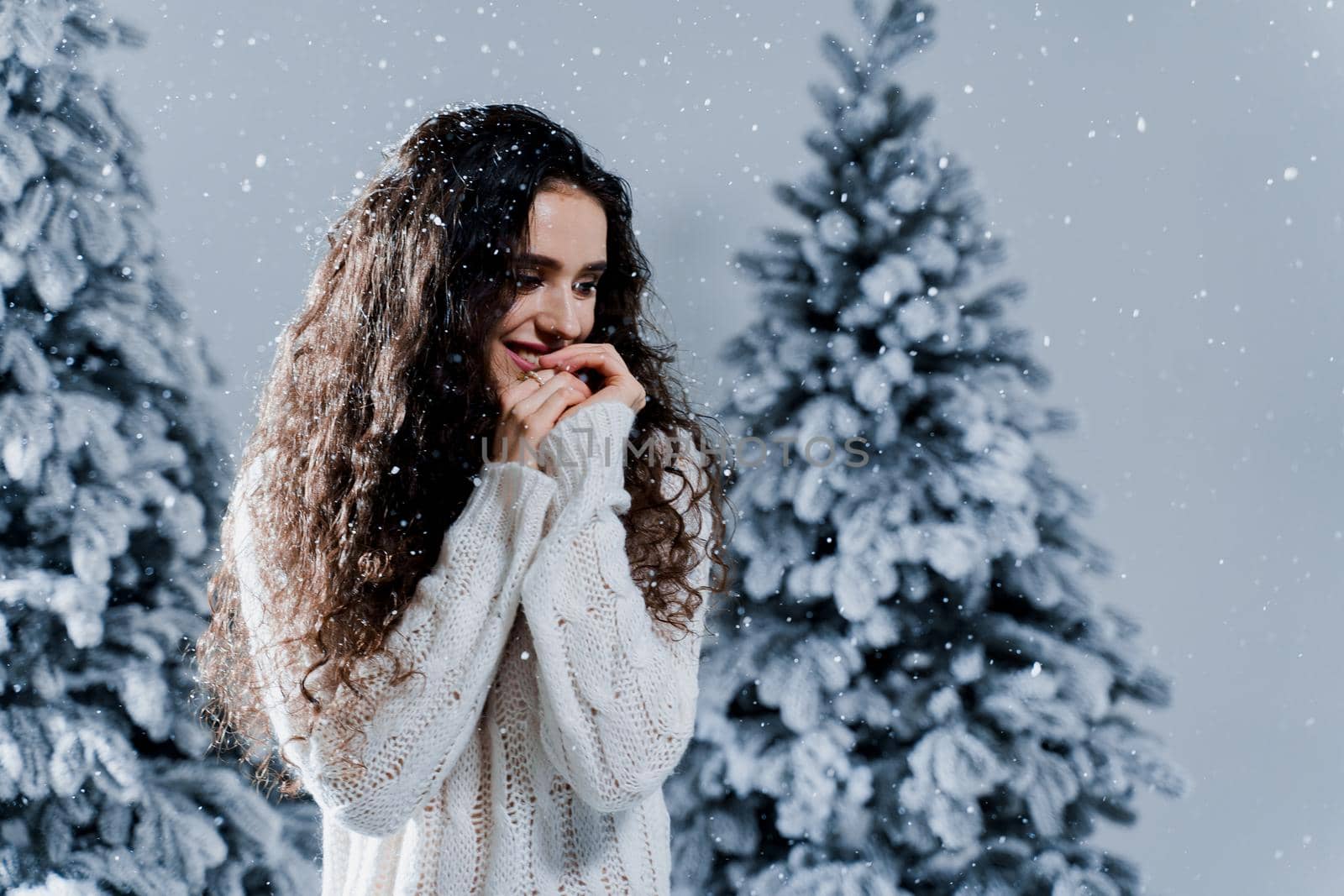 New year celebration.Happy girl with falling snow. Young woman weared in a warm white pullover and white socks. Winter holidays in snowy day