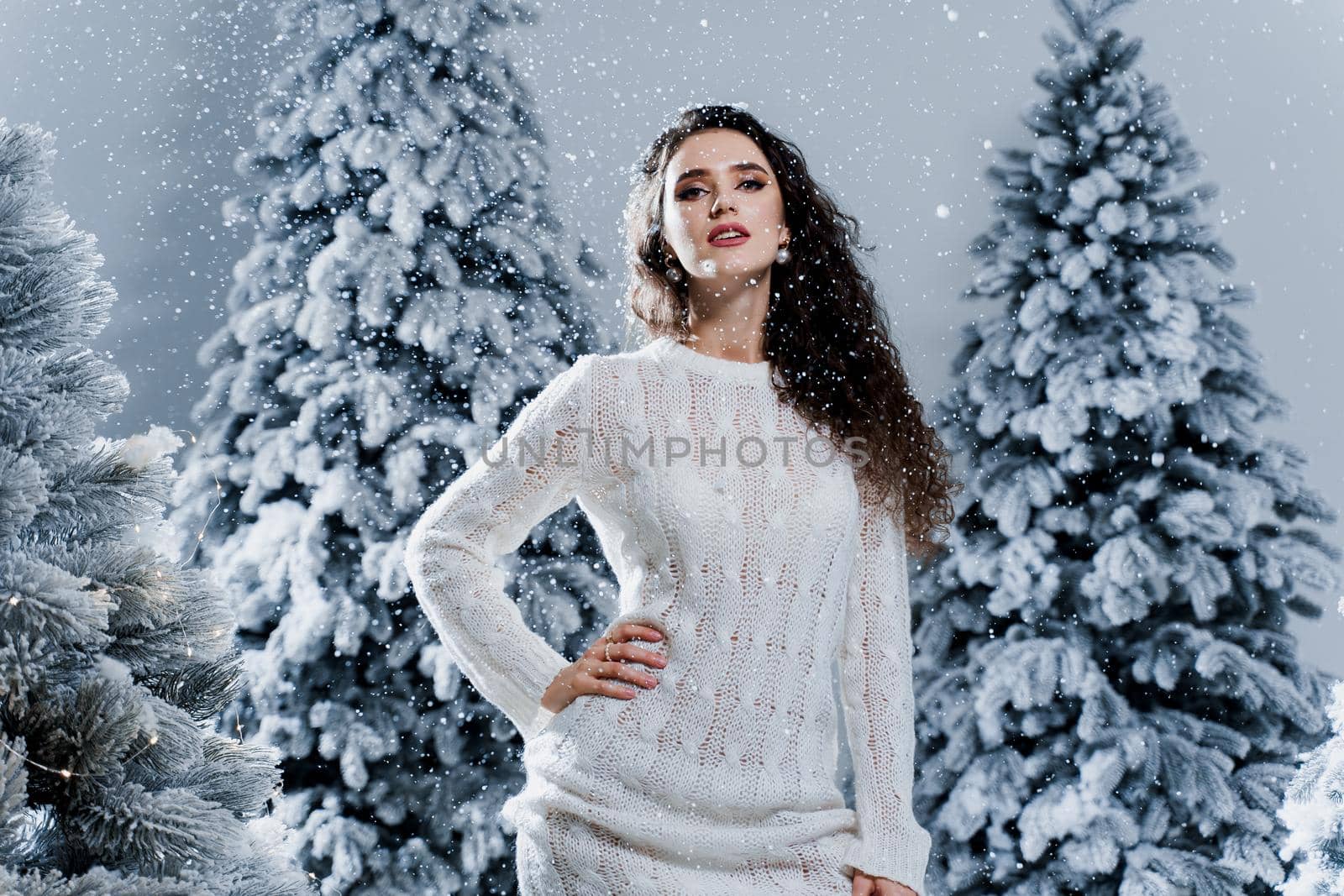 New year celebration.Happy girl with falling snow. Young woman weared in a warm white pullover and white socks. Winter holidays in snowy day. by Rabizo