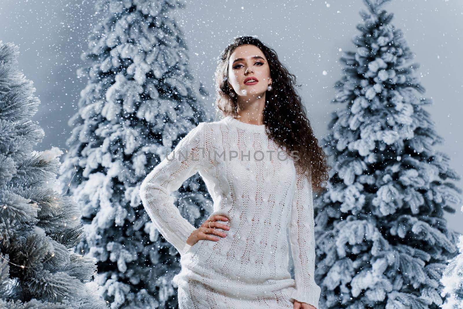 New year celebration.Happy girl with falling snow. Young woman weared in a warm white pullover and white socks. Winter holidays in snowy day