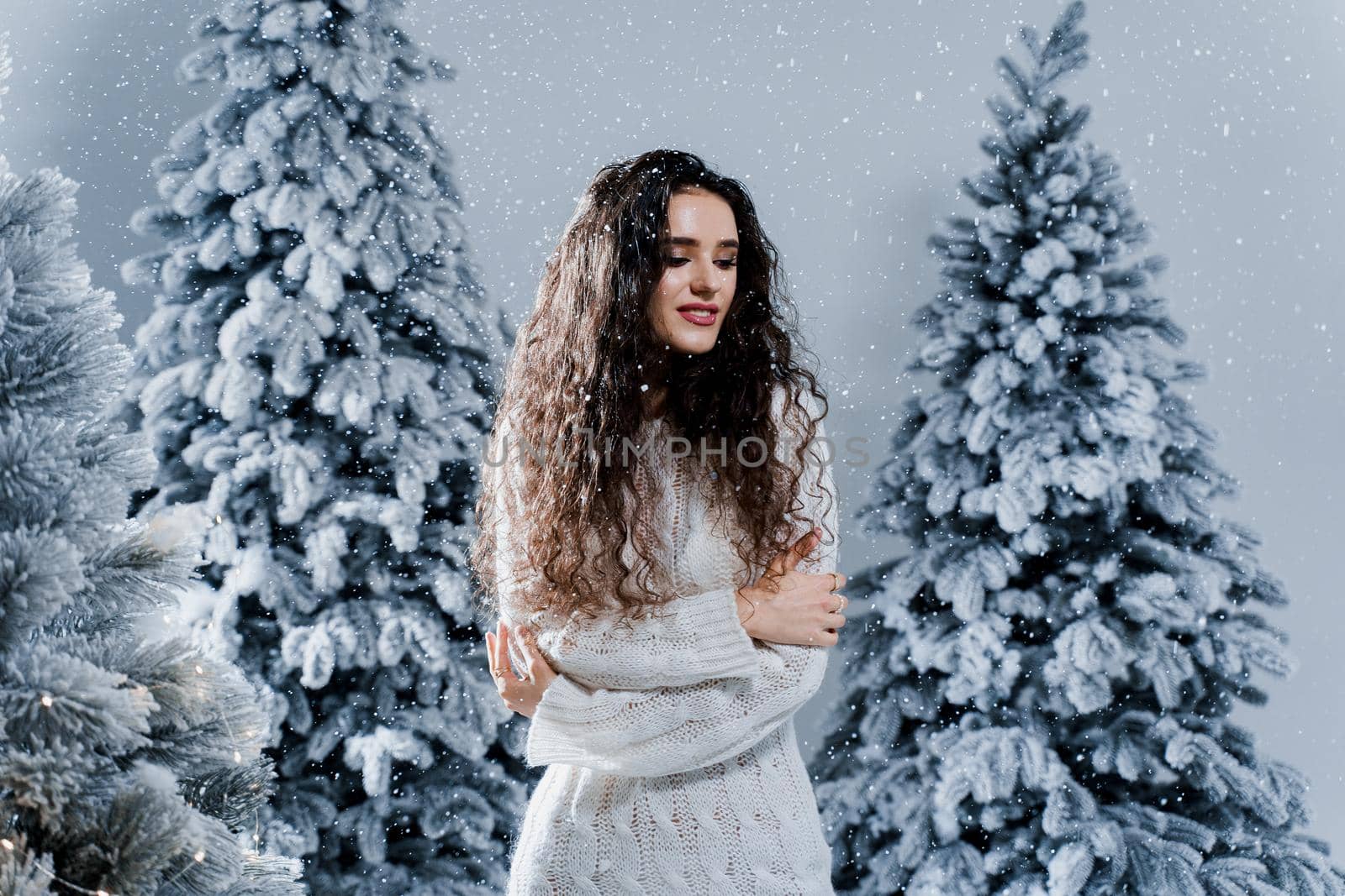New year celebration.Happy girl with falling snow. Young woman weared in a warm white pullover and white socks. Winter holidays in snowy day. by Rabizo