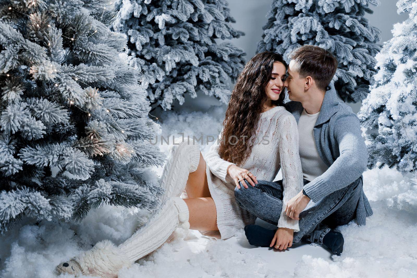 New year love story. Couple kiss and hug. Happy young couple near christmas trees in winter day by Rabizo