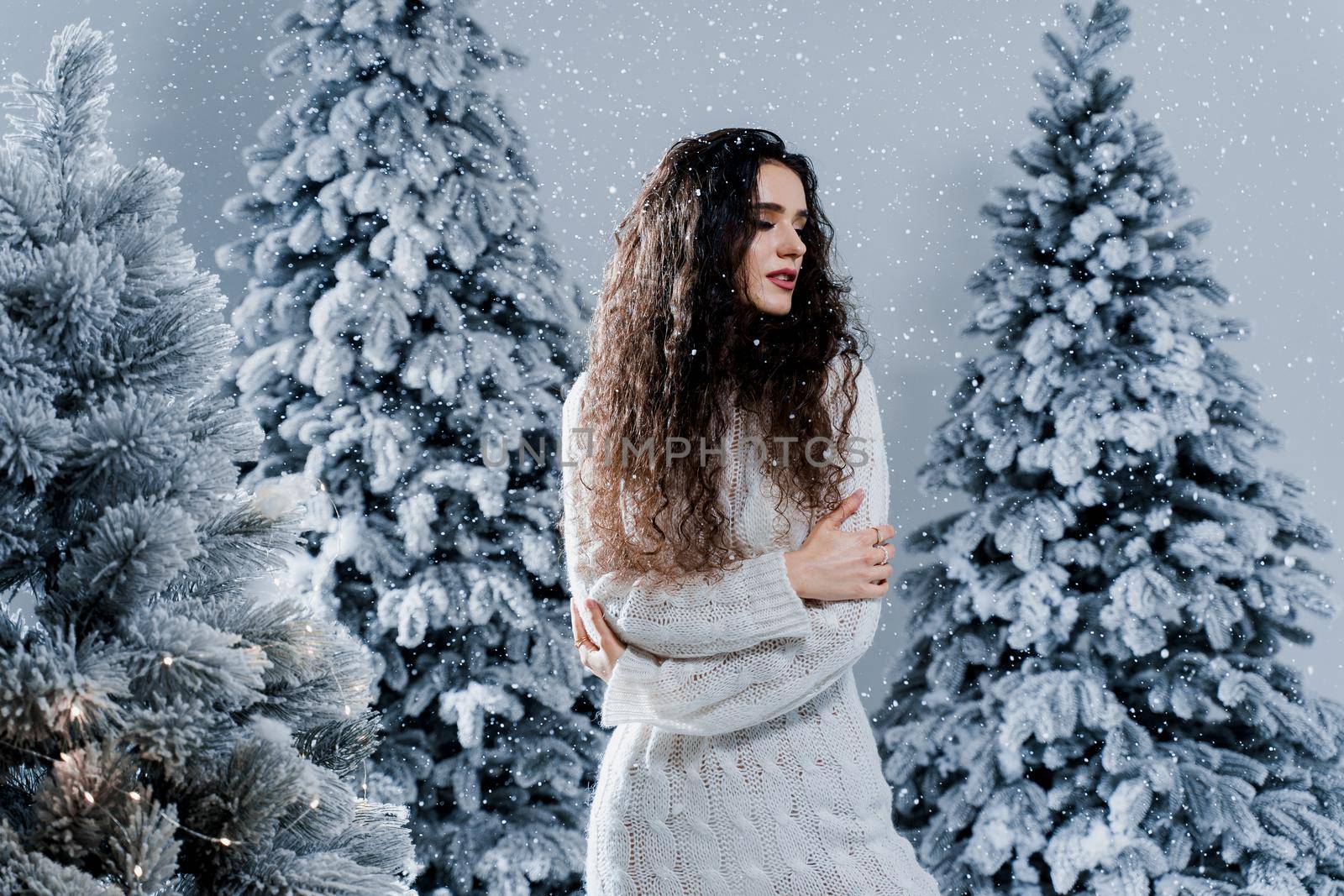 New year celebration.Happy girl with falling snow. Young woman weared in a warm white pullover and white socks. Winter holidays in snowy day. by Rabizo