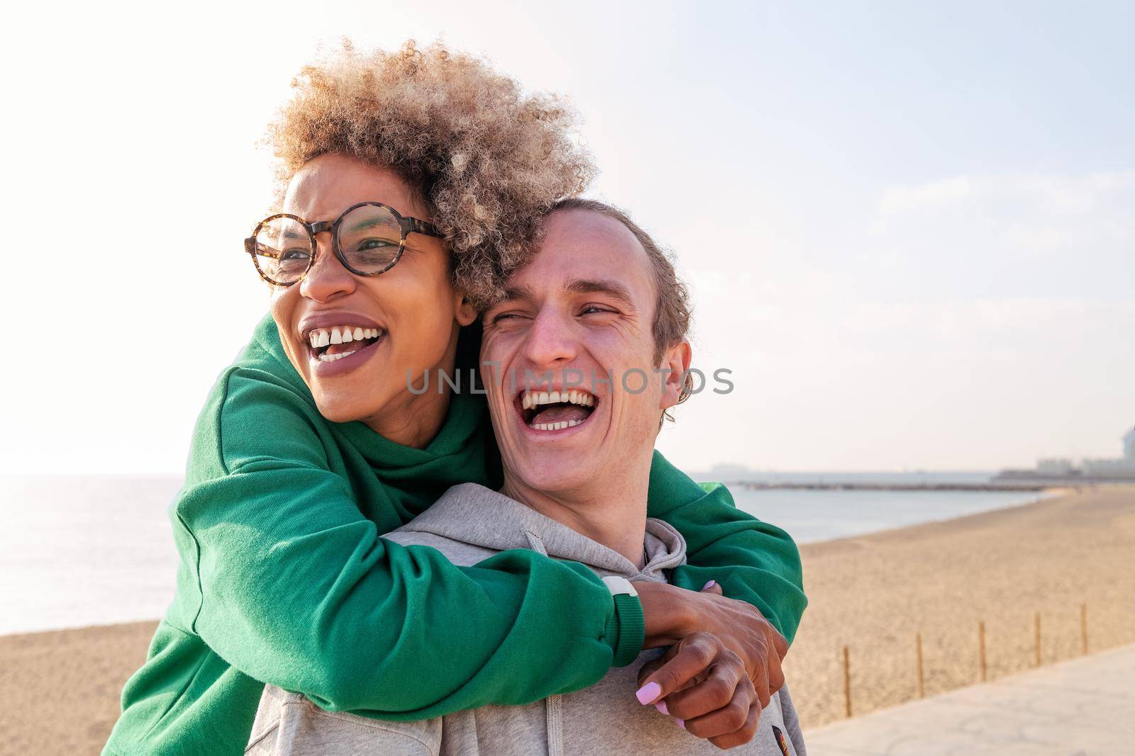happy young couple of latin woman and caucasian man hugging and laughing, concept of friendship and fun in a relationship, copy space for text