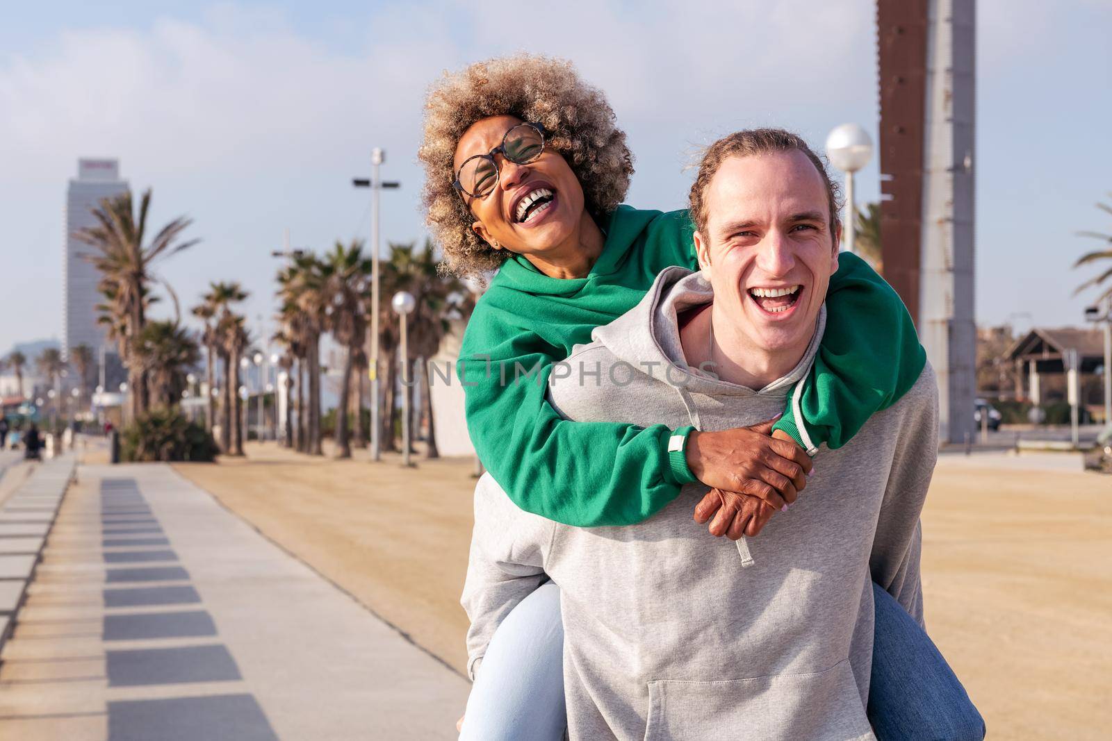 happy young couple laughing and having fun with the man piggybacking her girlfriend, concept of friendship and fun in a relationship, copy space for text