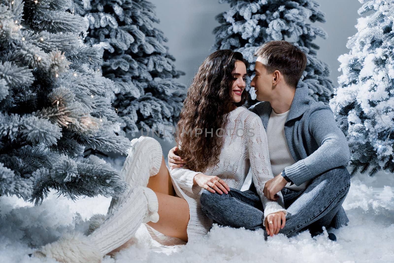 New year love story. Couple kiss and hug. Happy young couple near christmas trees in winter day by Rabizo