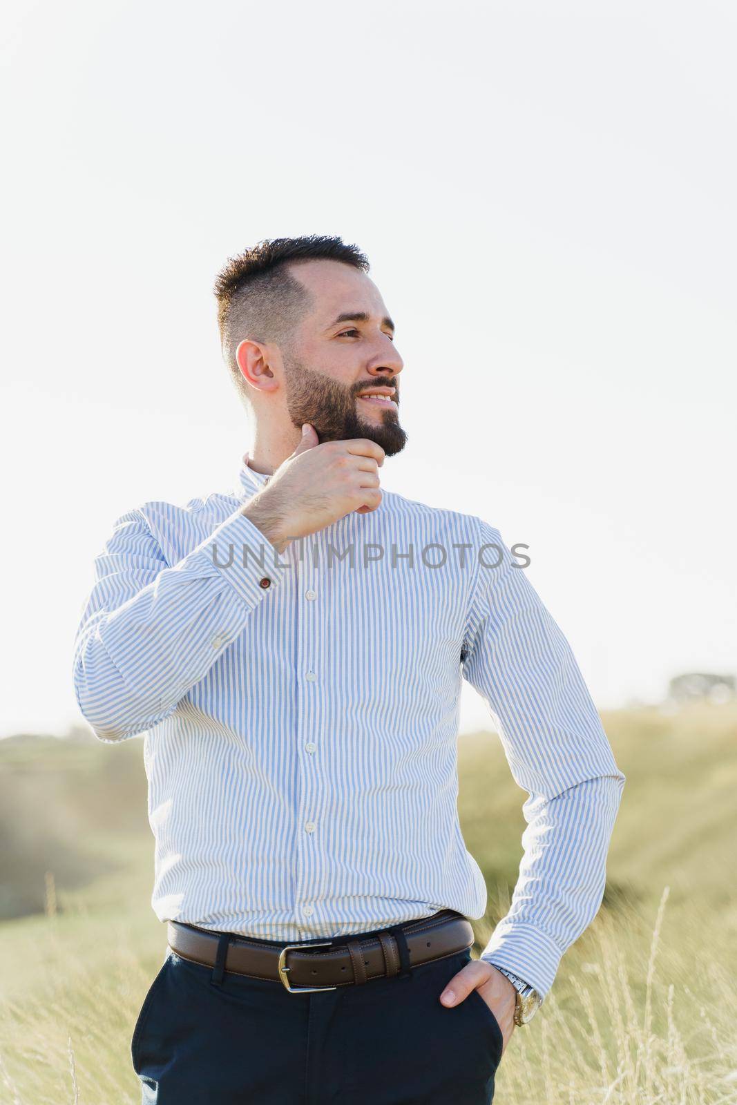 Handsome bearded arabian man in sunglasses on the green hills background. Confident muslim business man. Arab man weared in white shirt. by Rabizo