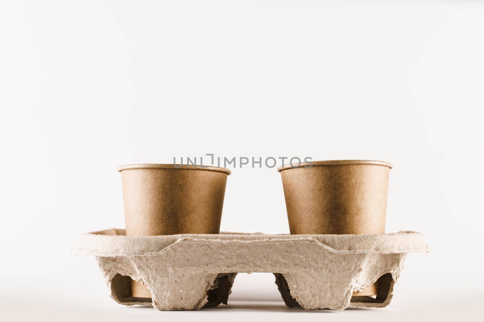 Eco friendly natural 4 coffee cup in cup holder in with empty space. Disposable ecological utensils on white background. Sustainability of planet. Cardboard glass made of fiber of bamboo and bagasse.