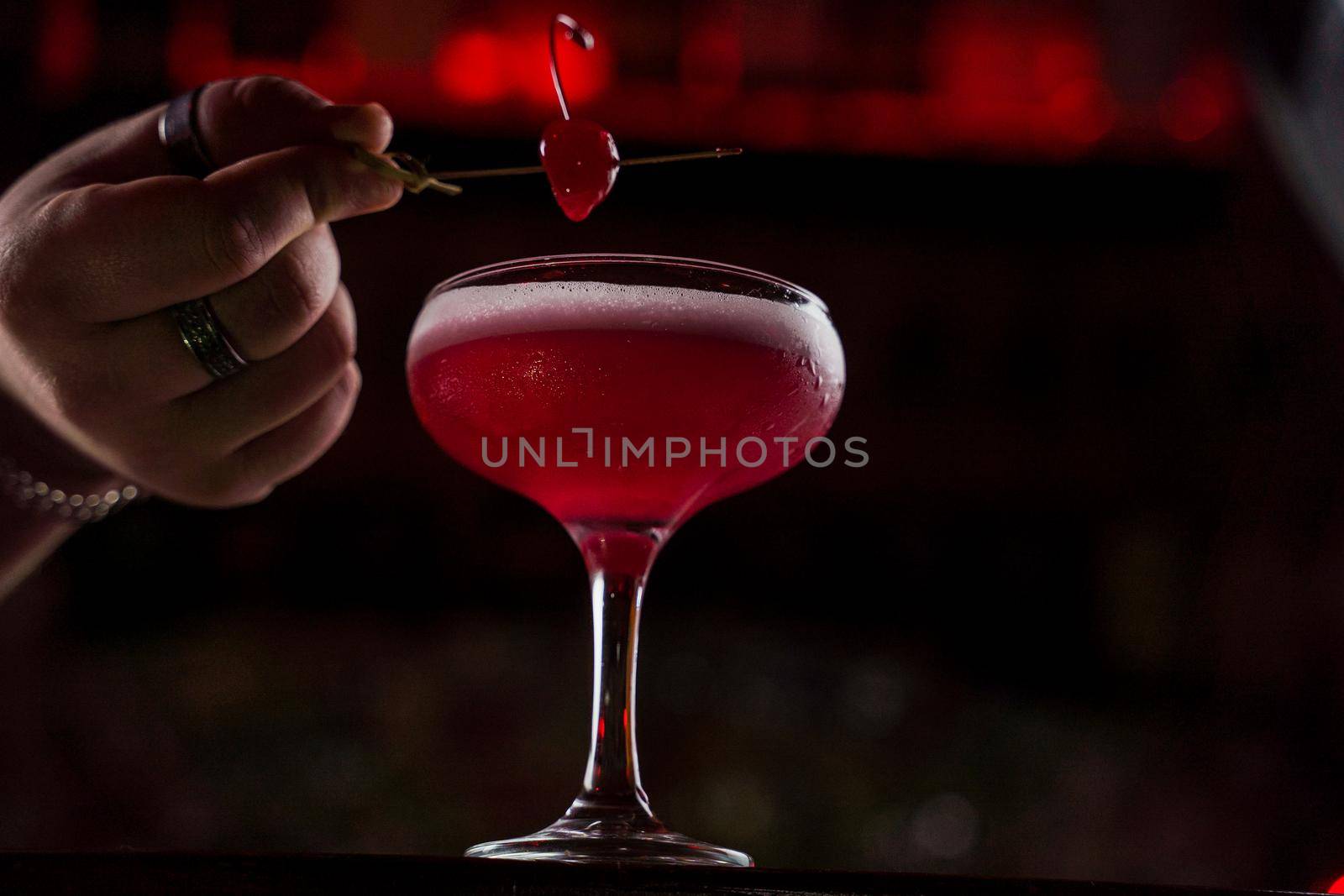 Classic Pink Lady cocktail closeup with flower and cherry on bar counter