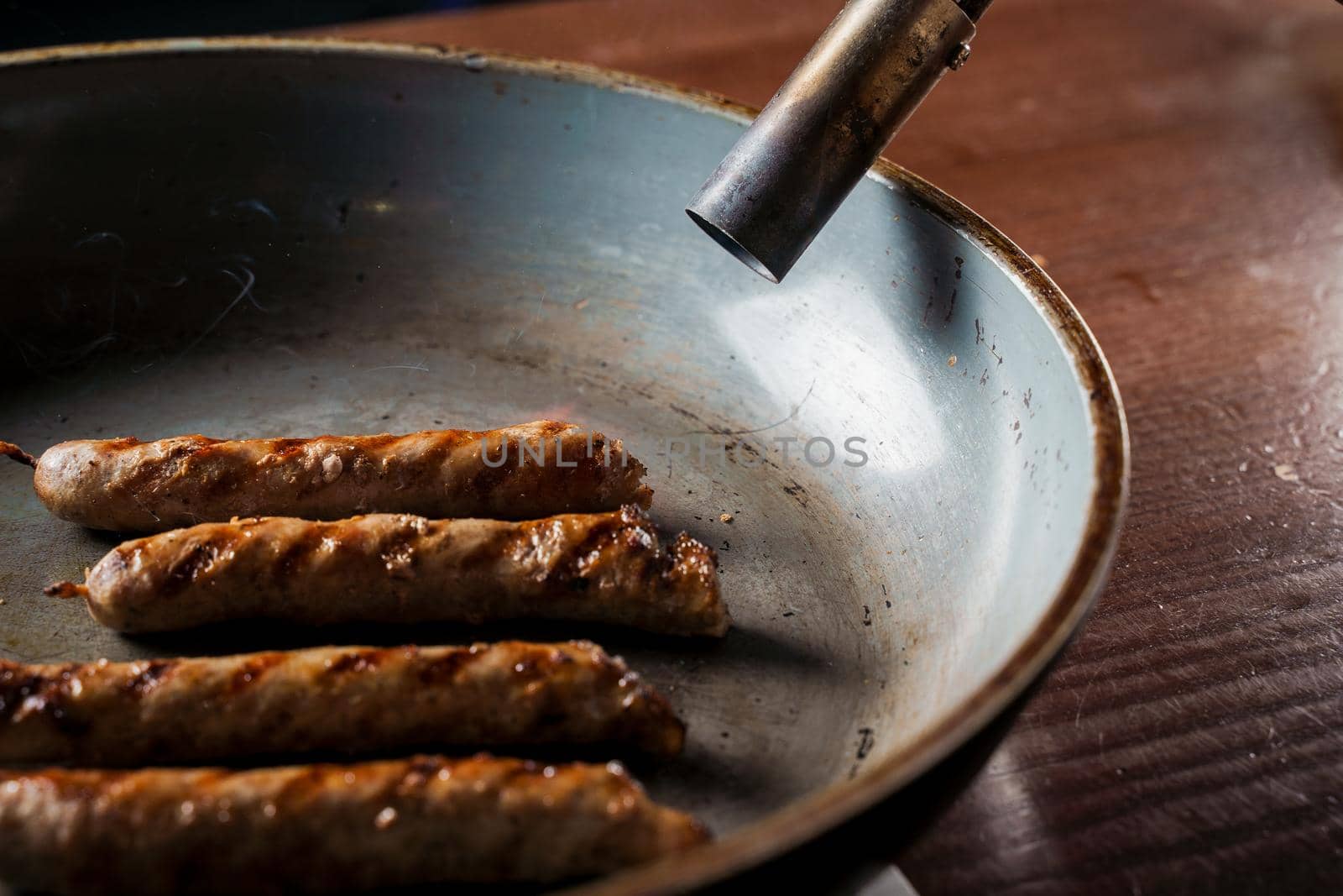 Grilled sausages in a frying pan are fired with a gas burner. by Rabizo