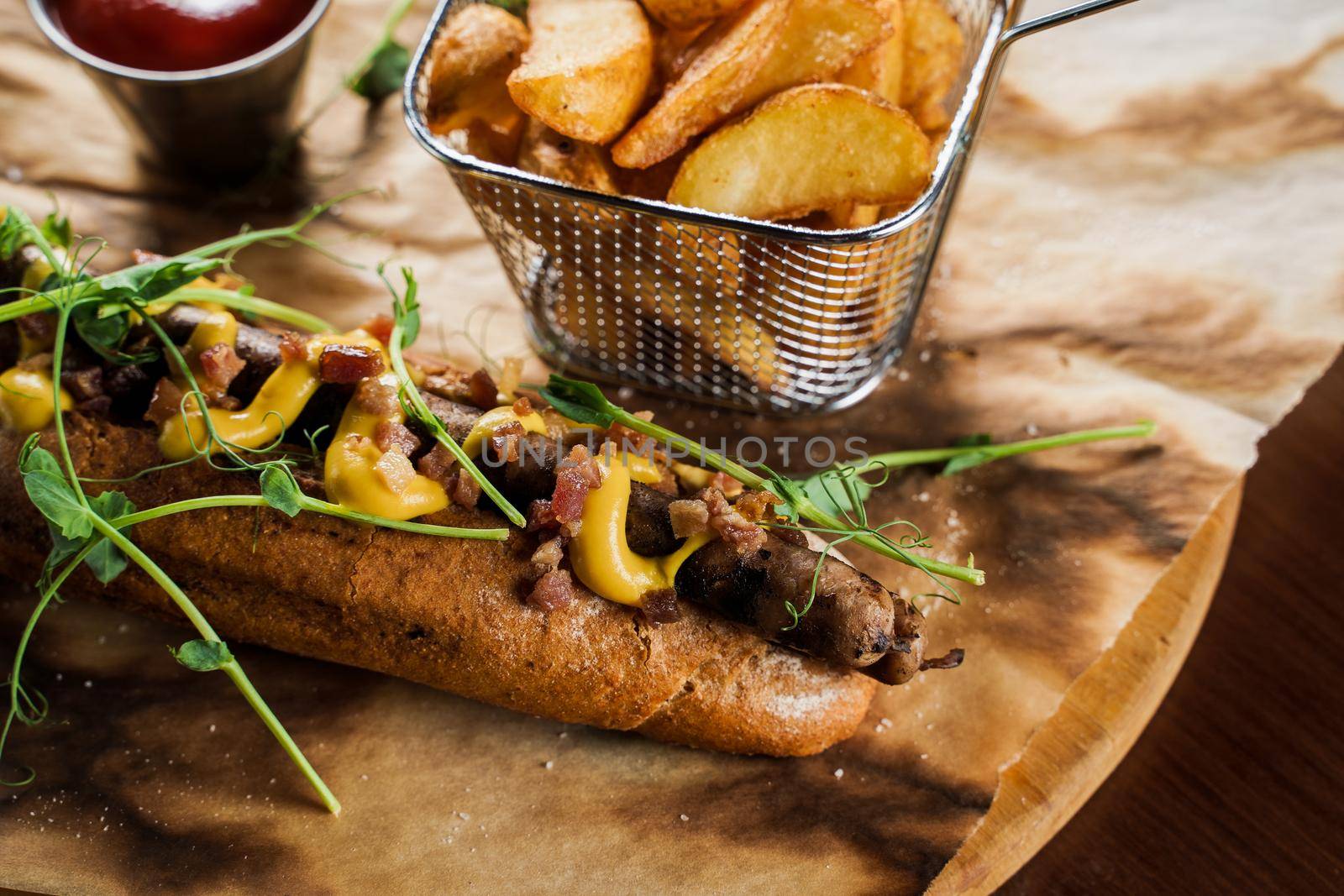 Barbecue grilled hot dog and beer with yellow mustard and ketchup on wooden background. Hot dog sandwich with potato fries and sauces.