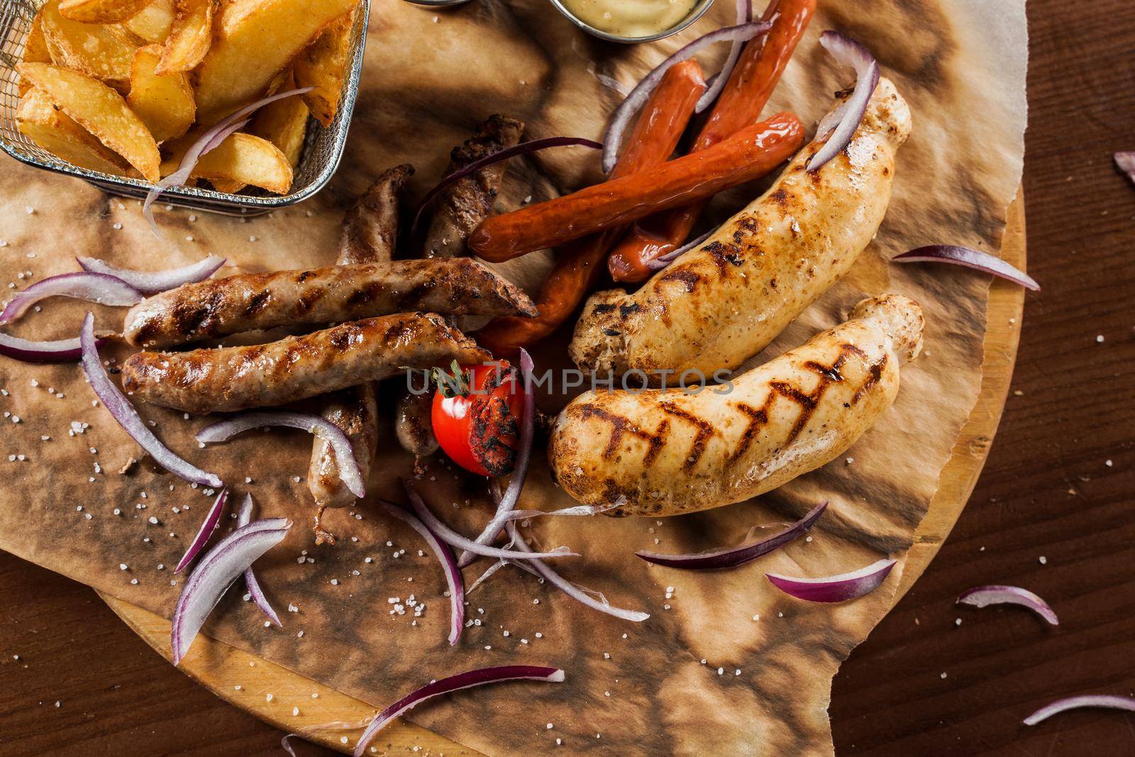 Barbecue grilled hot dog with yellow mustard and ketchup on wooden background. Hot dog sandwich with potato fries and sauces.