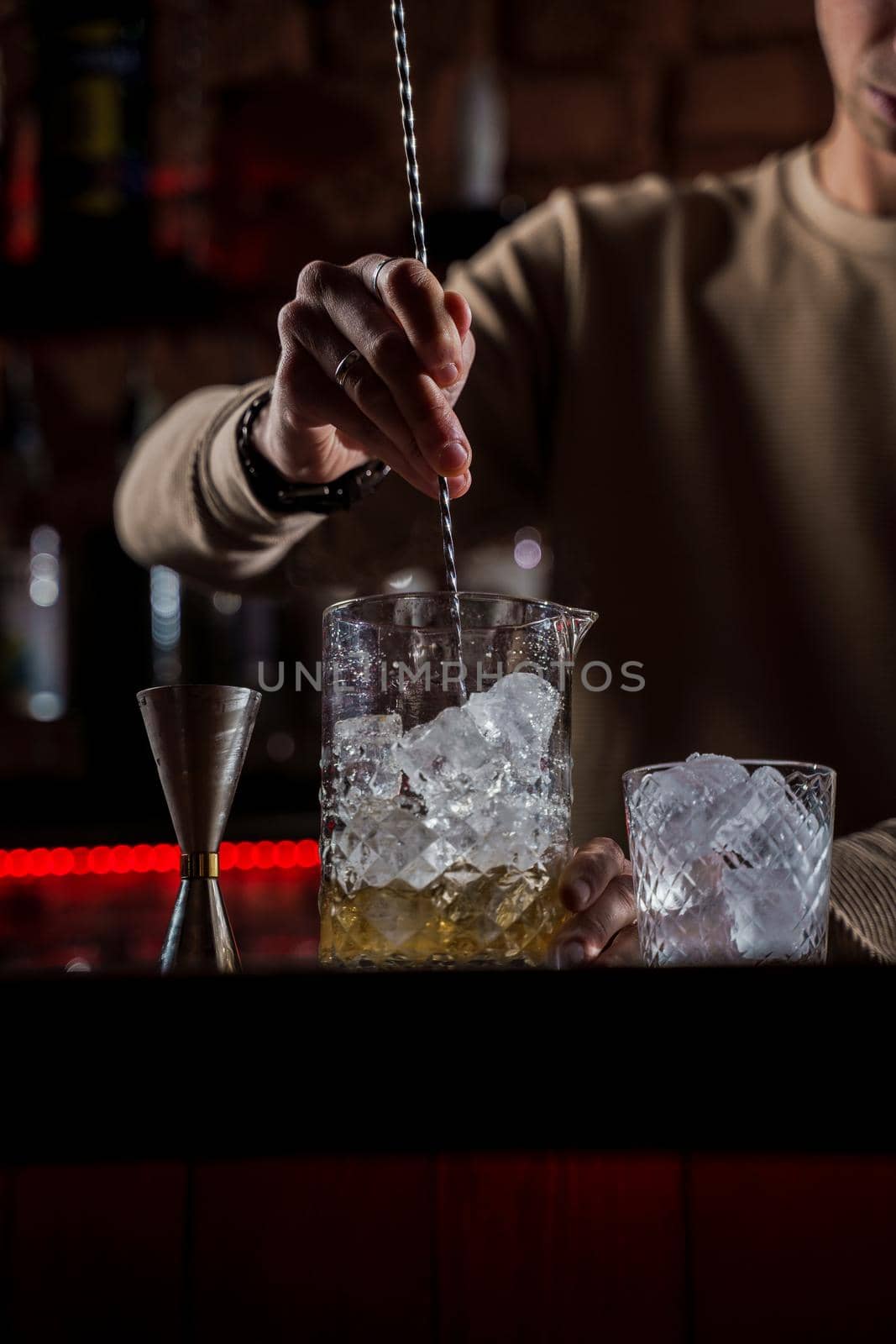 Barman make alcohol cocktail at bar counter. Barman making Jungle Juice coctail in bar. by Rabizo