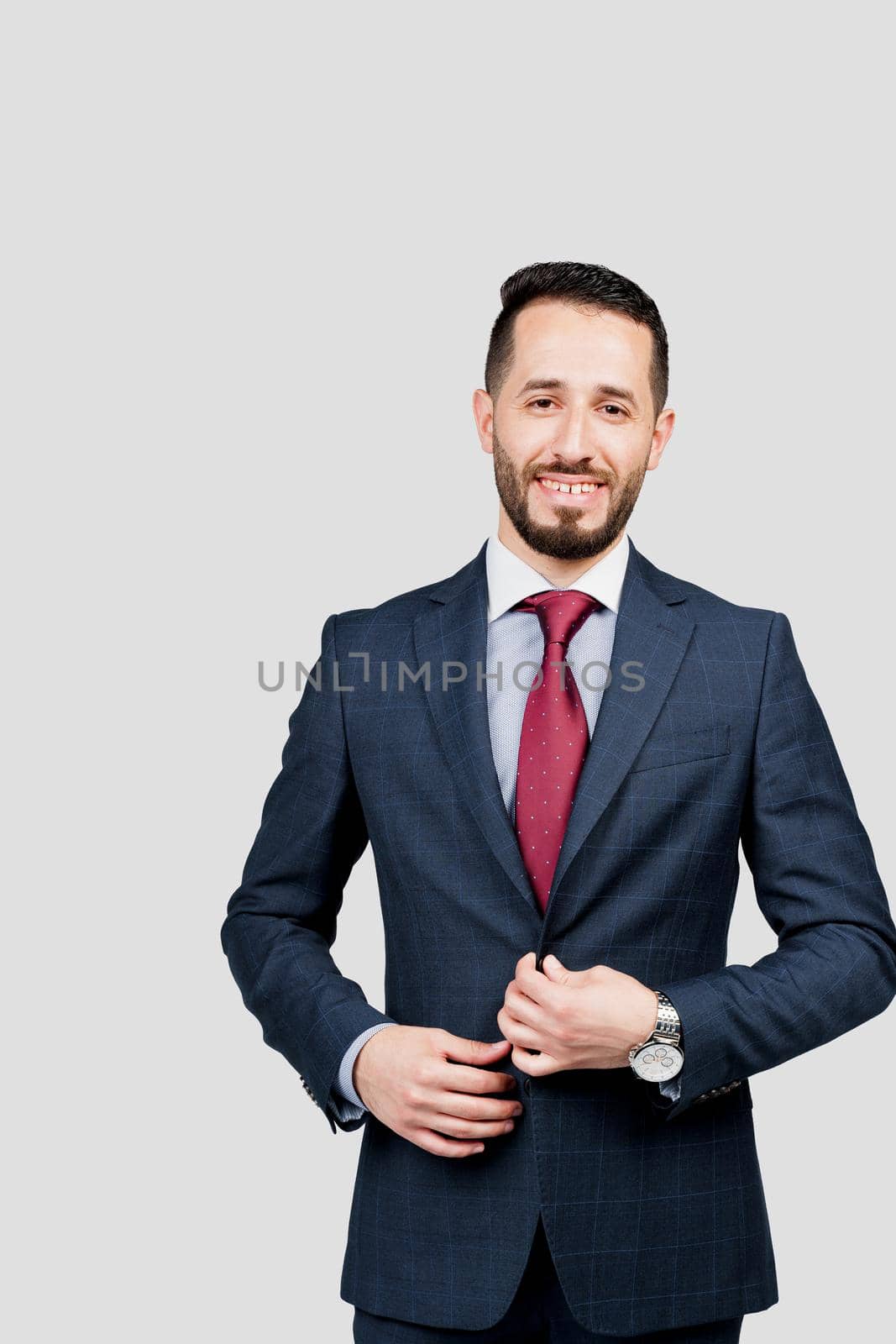 Handsome arabic businessman in suit smiles on white blank background in studio. Business portrait of successful man