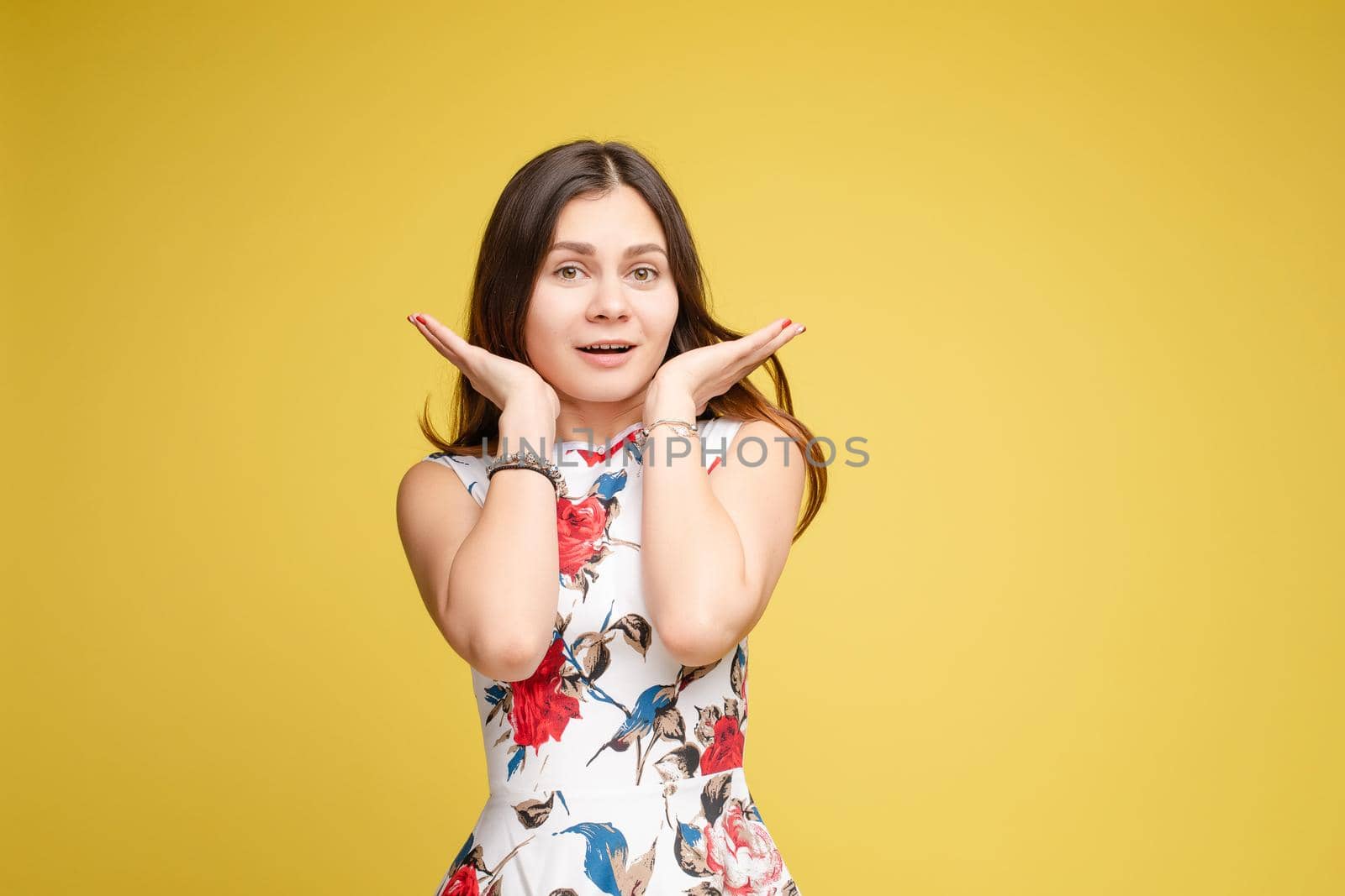 Front view of surprised young girl in bright dress looking at camera on yellow isolated background in studio. Funny amazed female with open eyes shouting. Concept of shock and happiness.