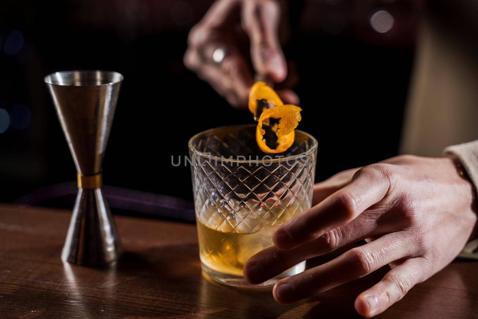 Orange peel in alcohol cocktail at bar counter. Barman making Jungle Juice coctail in bar