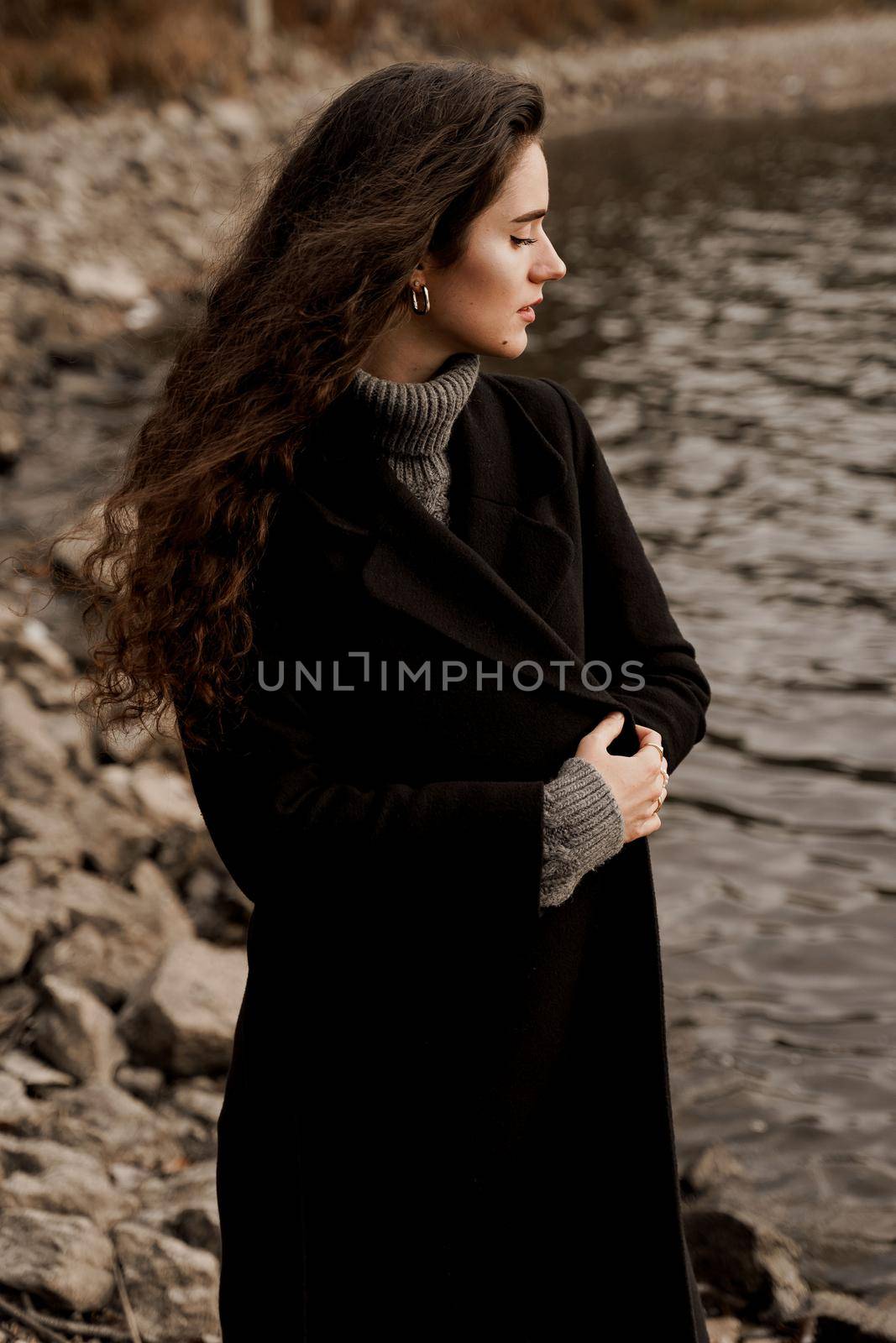 Attractive girl tourist travels around her country. Young woman with curly hair looks at the lake and dreams about her life