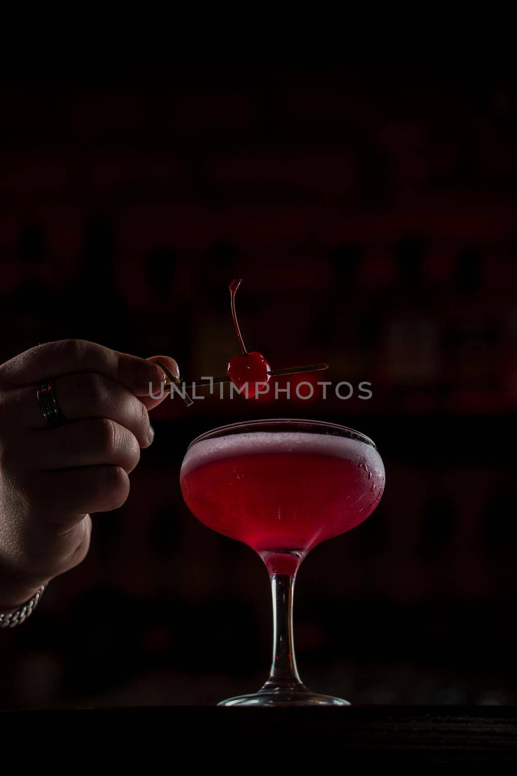 Classic Pink Lady cocktail closeup with flower and cherry on bar counter
