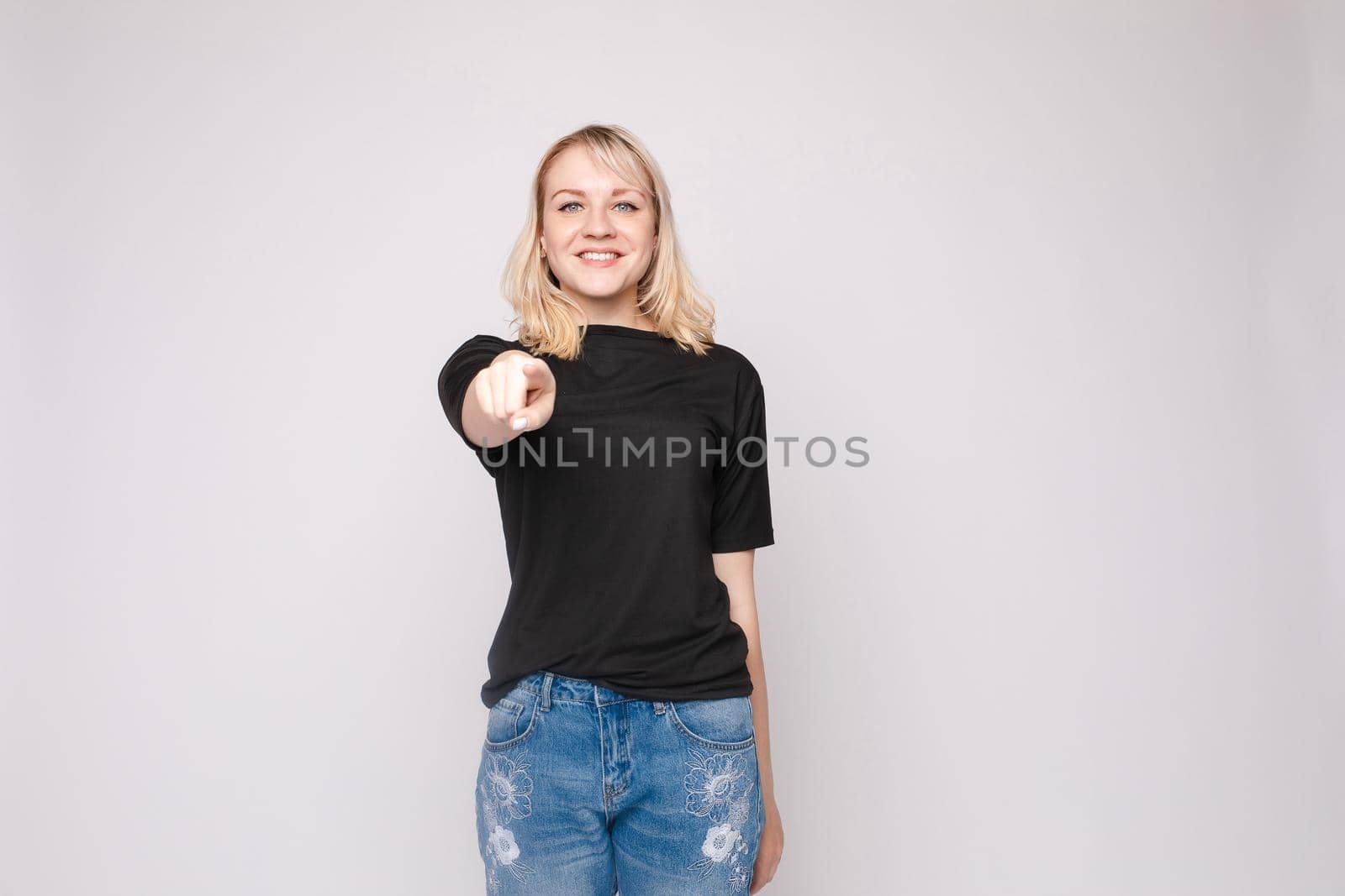 Confident young beautiful woman showing by hand stringent looking at camera posing isolated by StudioLucky