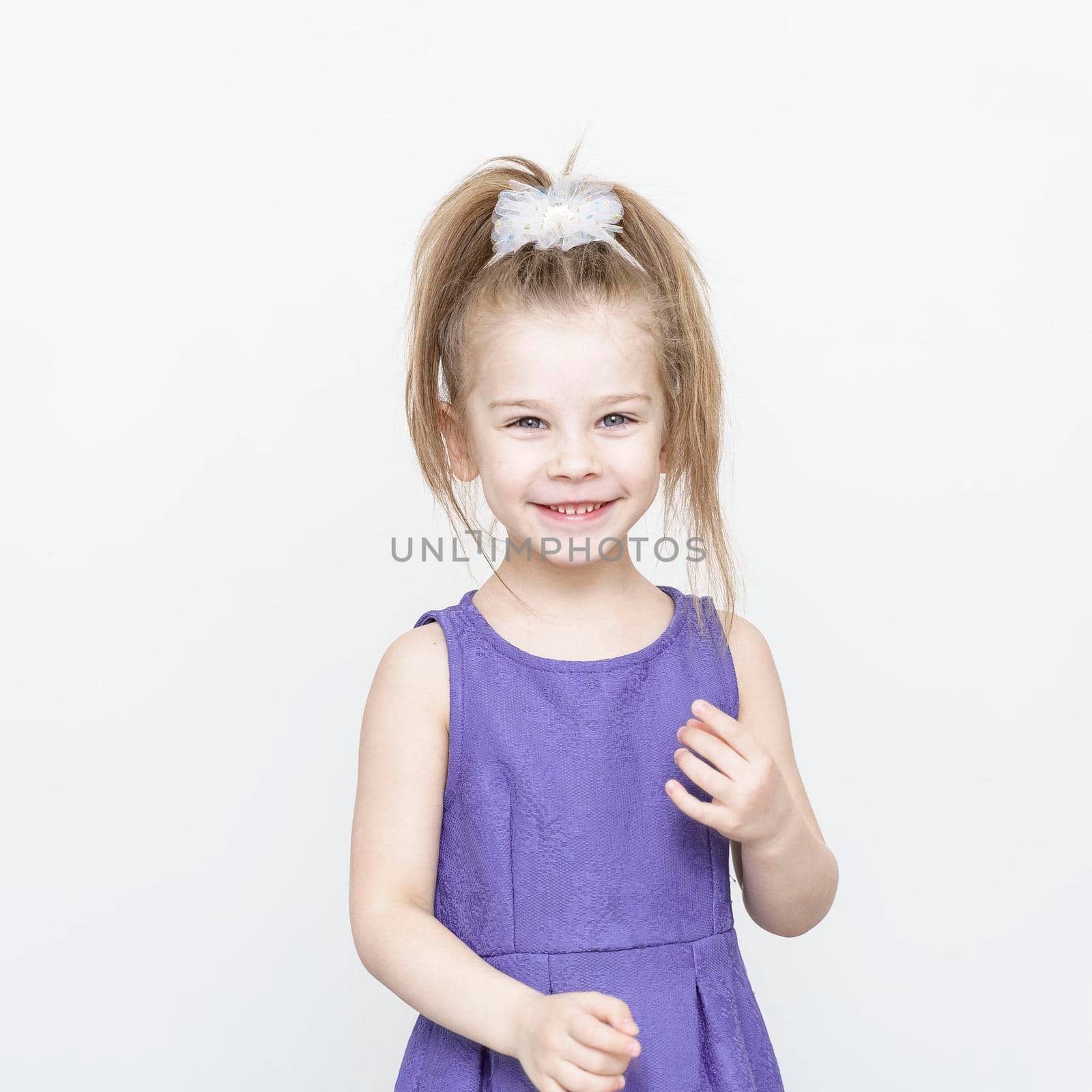 cute 5-6 year old girl in a blue dress posing in the studio