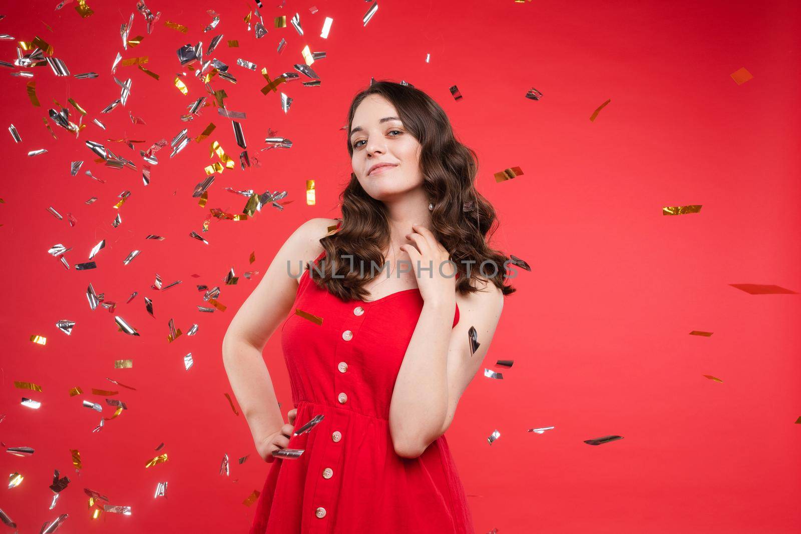 Brunette in red dress posing while sparkles falling around by StudioLucky