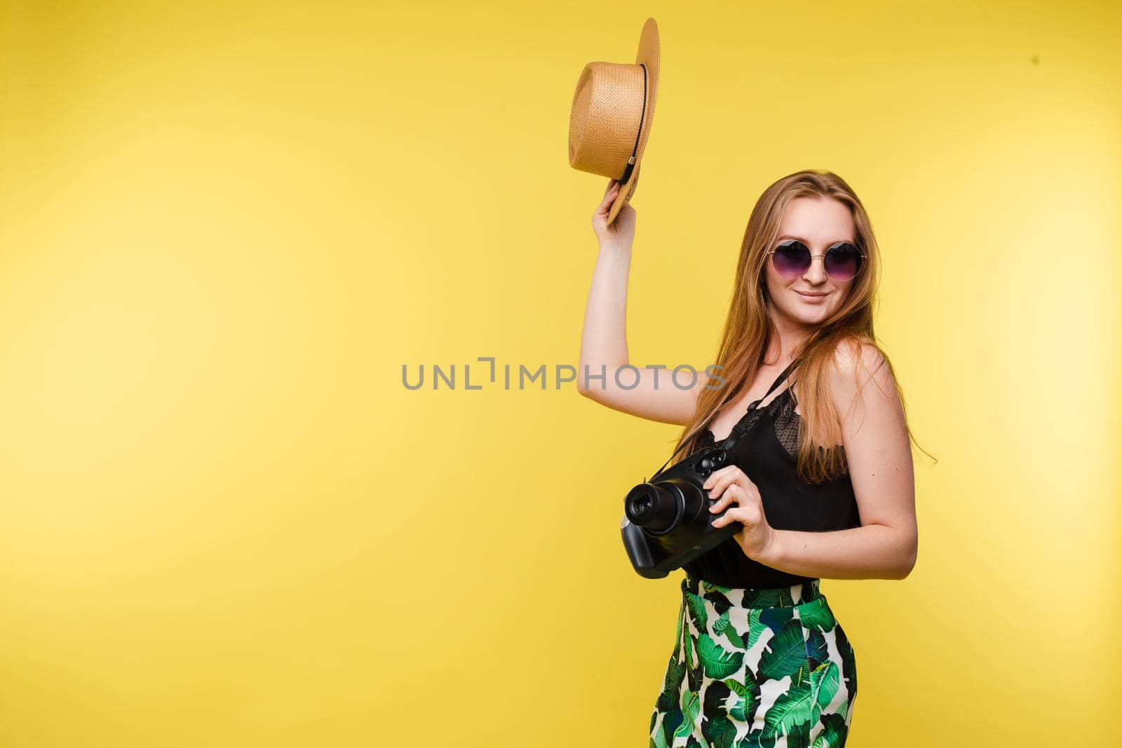 Young girl in straw hat and glasses keeping camera by StudioLucky