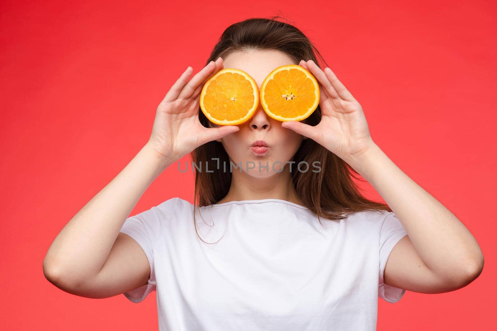 Funny fashionable girl with hairstyle holding oranges on eyes. by StudioLucky