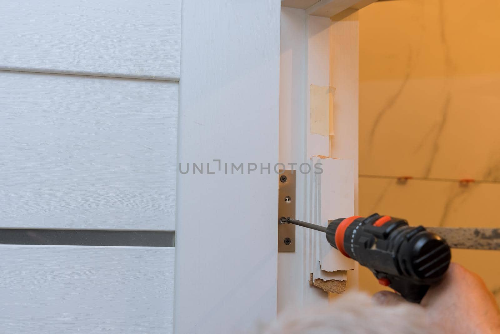 Process of installation stainless door hinges on a white wood door with screwdriver