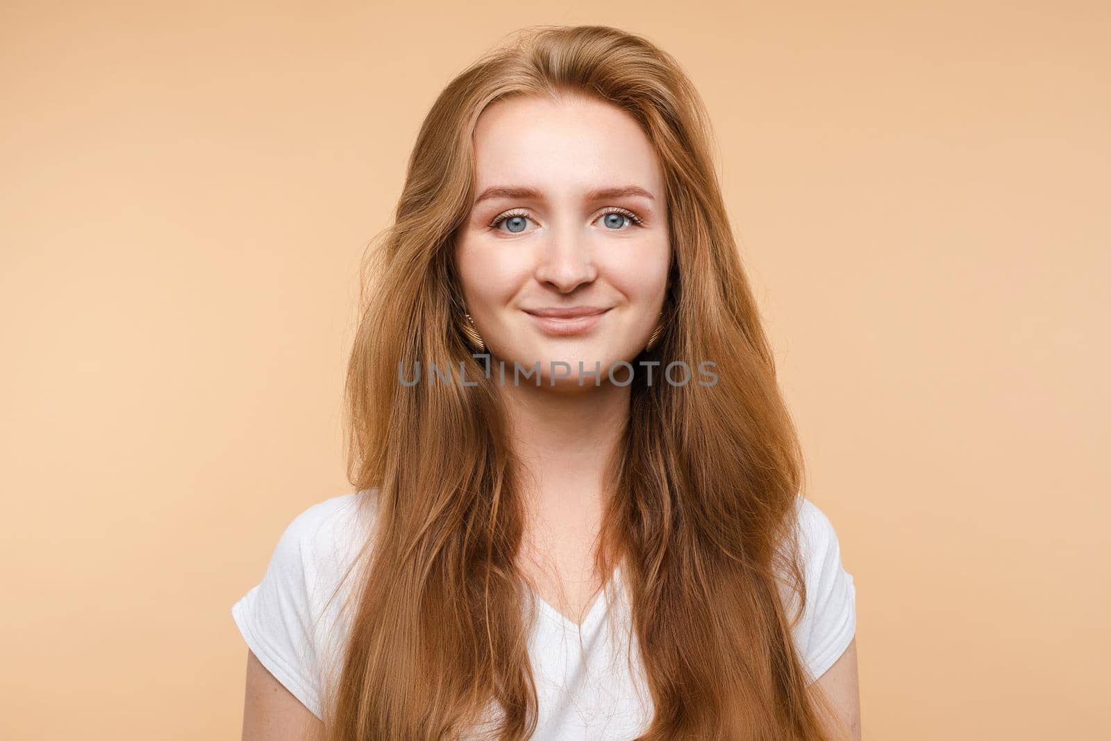 Portrait of beautiful smiling young red hair girl posing looking at camera medium close-up. Attractive European friendly woman having positive emotion isolated at yellow studio background